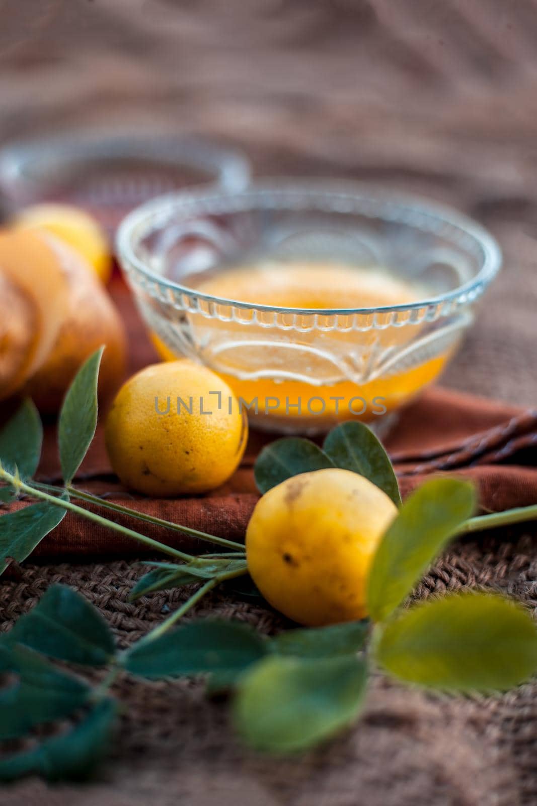 Glowing face mask of potato juice in a glass bowl on brown colored surface along with some lemon juice,potato juice and honey.Horizontal shot.
