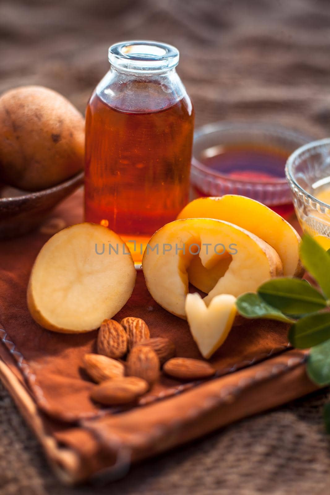 Glowing face mask of potato juice in a glass bowl on brown colored surface along with some Potato juice,honey and almond oil.Horizontal shot.To eliminate skin rashes, remove impurities,etc. by mirzamlk