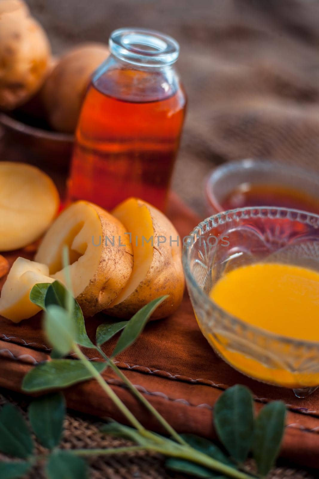 Glowing face mask of potato juice in a glass bowl on brown colored surface along with some Potato juice,honey and almond oil.Horizontal shot.To eliminate skin rashes, remove impurities,etc.