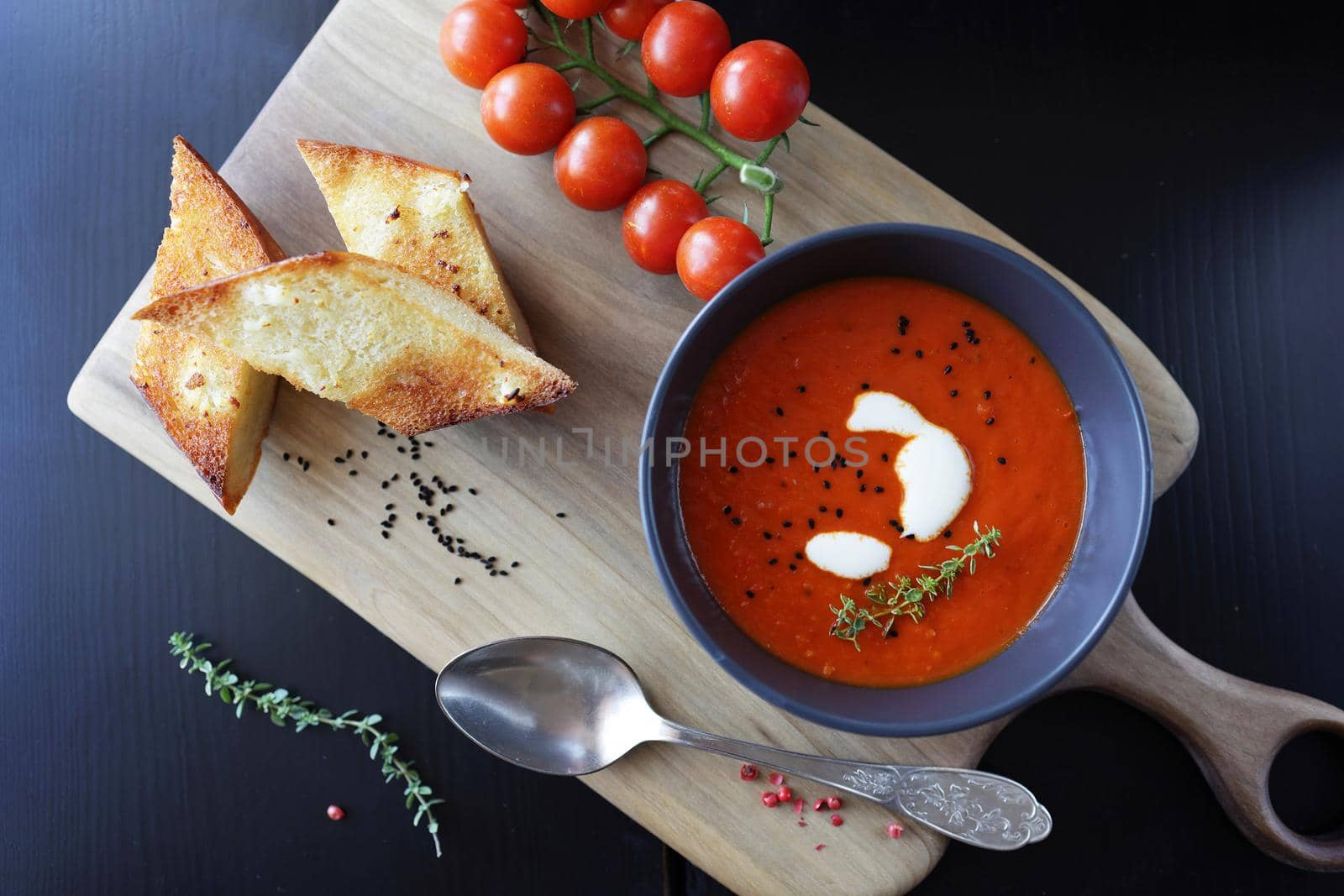 Tomato soup with thyme in a bowl. Dark background. Close up. Top view.