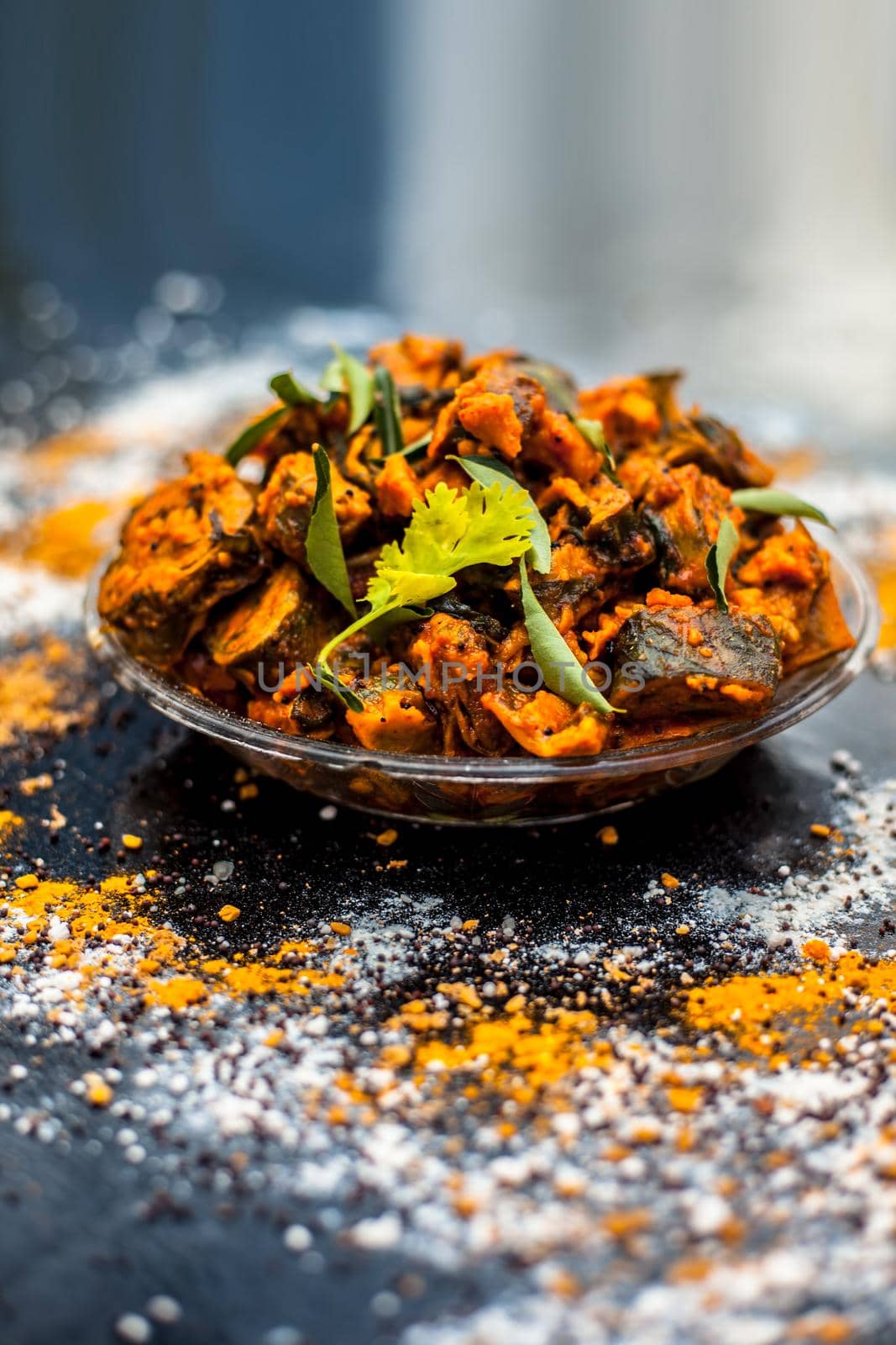 Famous Indian & Gujarati snack dish in a glass plate on wooden surface i.e. Patra or paatra consisting of mainly Colocasia esculenta or arbi ke pan or elephant ear leaves and spices. Vertical shot.