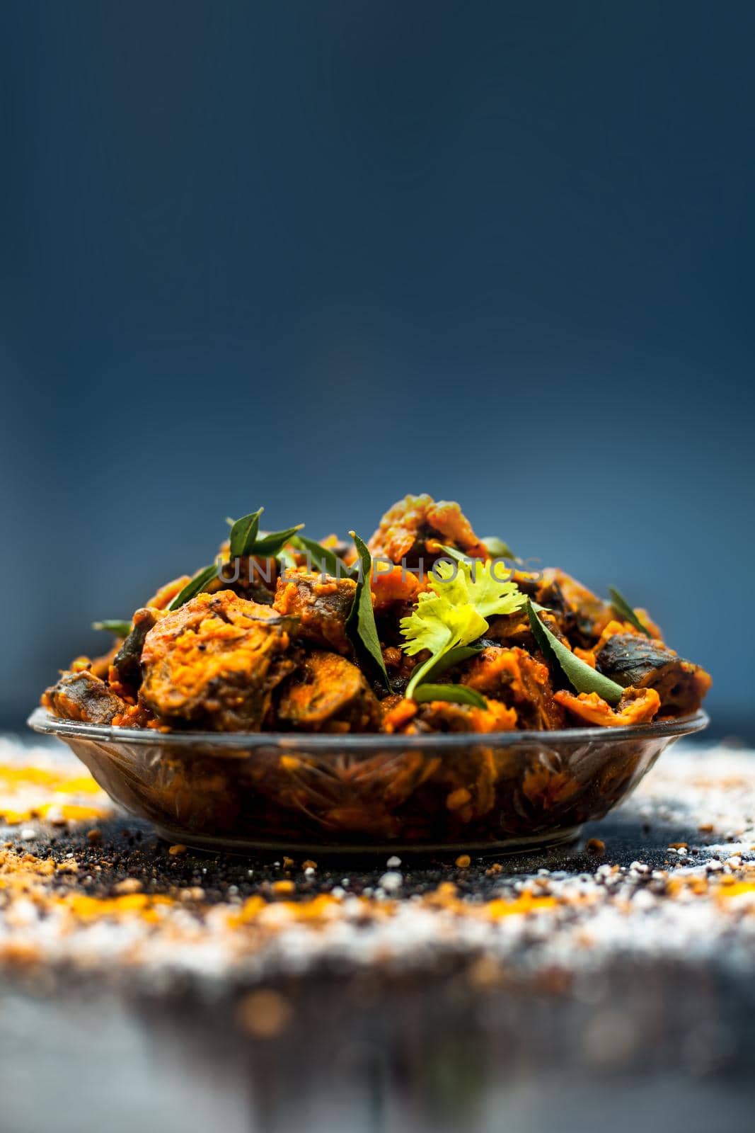 Famous Indian & Gujarati snack dish in a glass plate on wooden surface i.e. Patra or paatra consisting of mainly Colocasia esculenta or arbi ke pan or elephant ear leaves and spices. Vertical shot. by mirzamlk