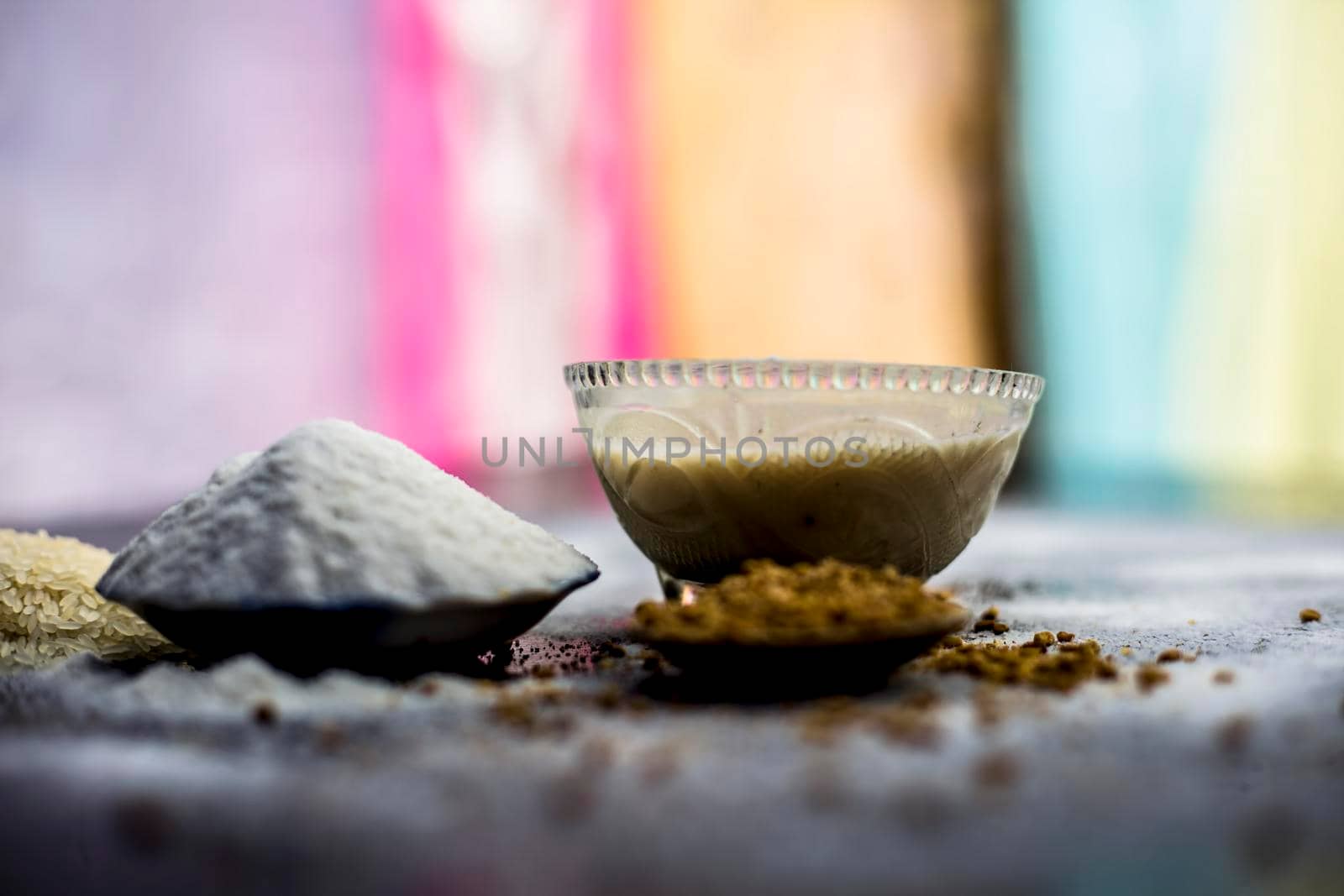 Hair growth remedy of rice flour water and fenugreek/coriander/parsley seeds powder on wooden surface and its paste in a glass bowl with some rice flour spread on the surface. by mirzamlk