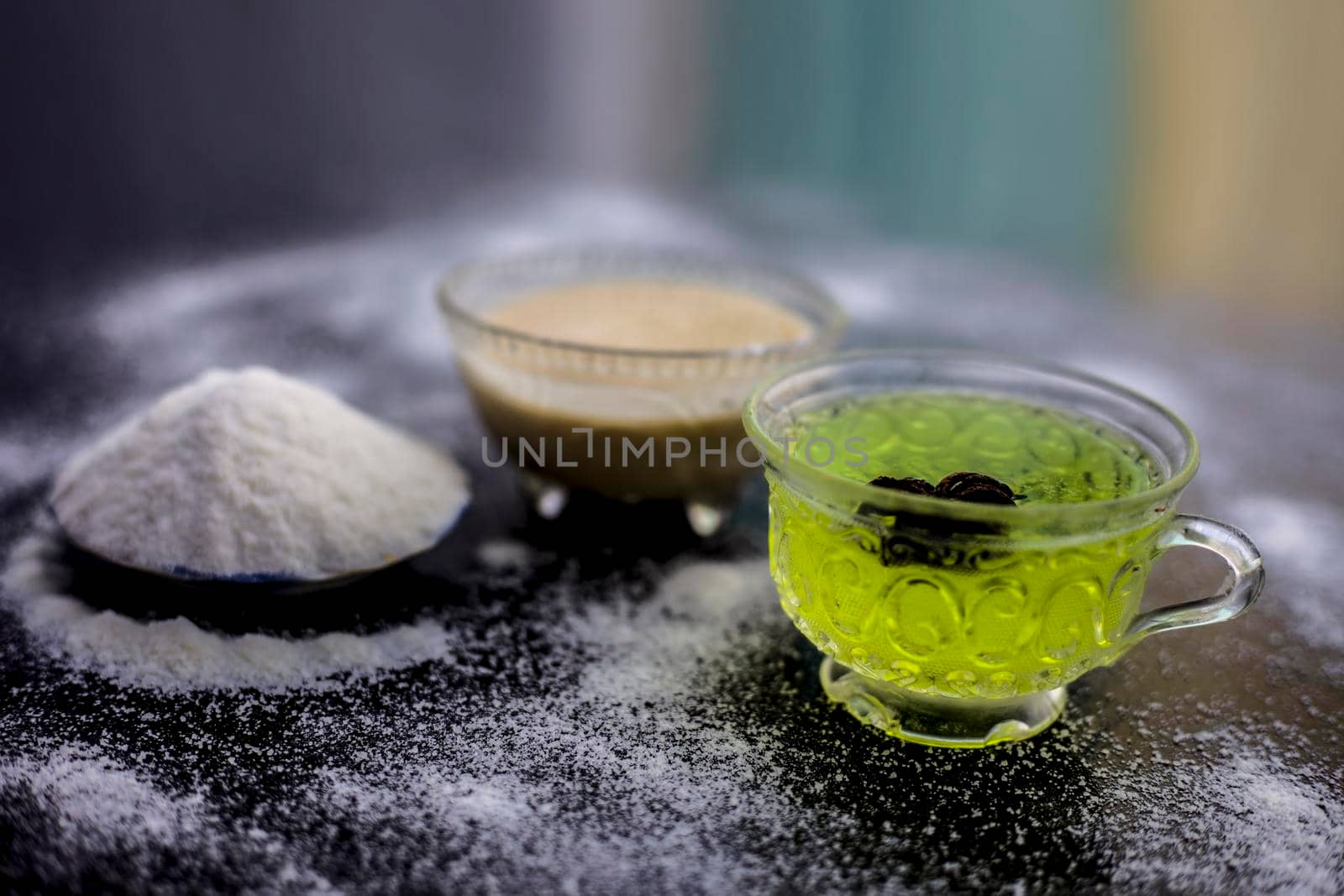 Rice flour and rice grain on wooden surface along with some green tea in a transparent glass cup and a star anise in it.Face mask for the treatment for smoother skin.