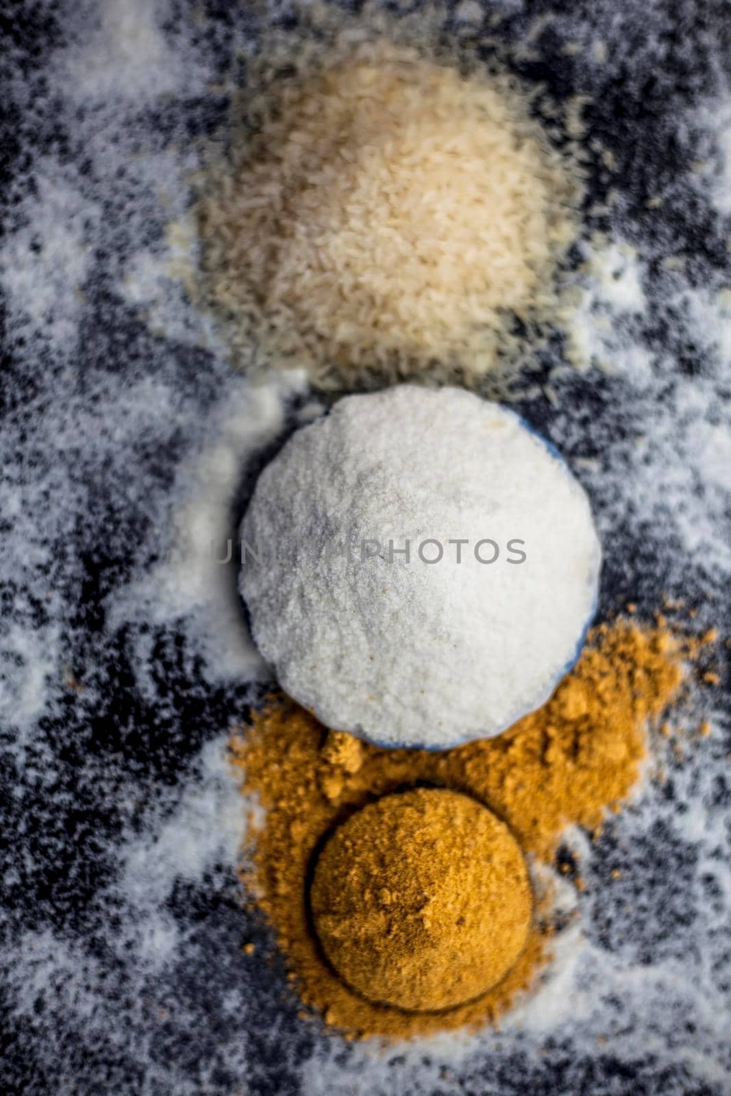 Face mask for glowing skin on wooden surface consisting of rice flour & dried orange peel powder in a glass bowl along with some rice flour spread on the surface for greater effect.Vertical shot. by mirzamlk