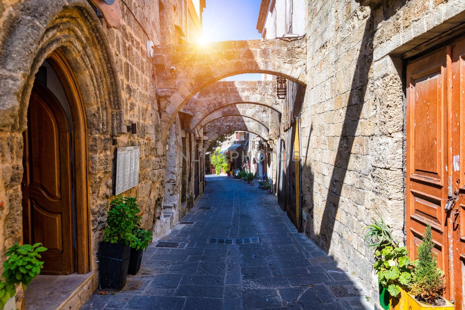 Medieval arched street in the old town of Rhodes, Greece. Rhodes old town in Rhodes island in Greece. Historical streets of old town Rhodes with flowers in Rhodes, Dodecanese, Greece