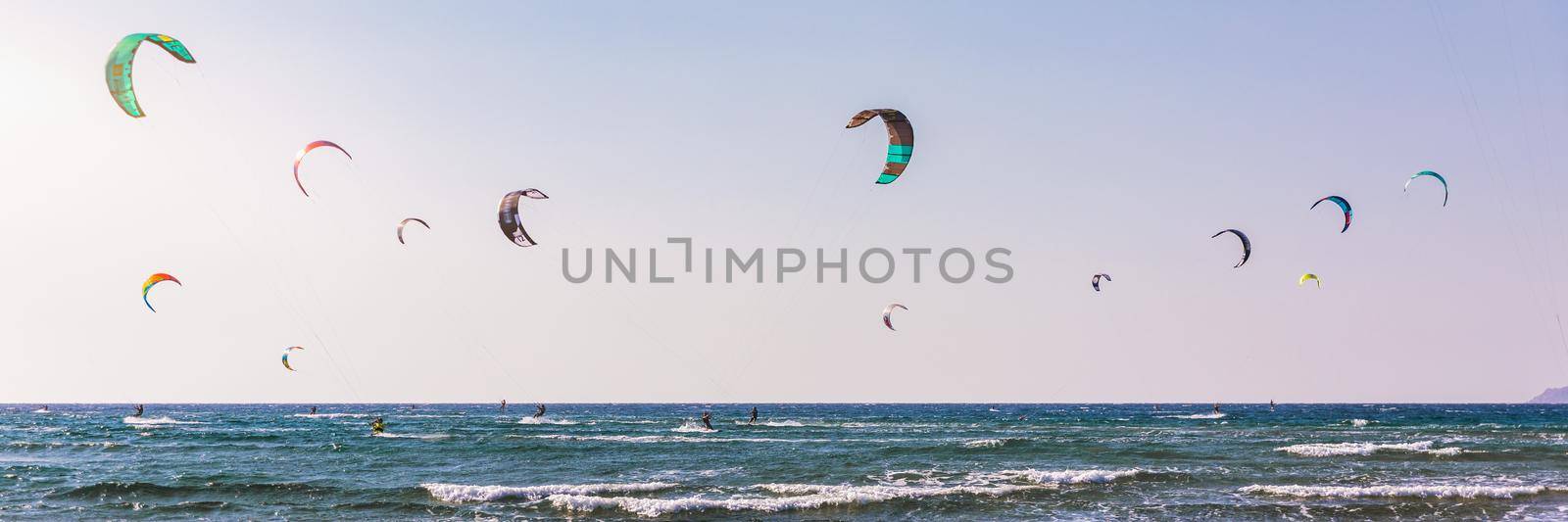 Surfers in Prasonisi Beach in Rhodes island, Greece. Kiteboarder kitesurfer athlete performing kitesurfing kiteboarding tricks. Prasonisi Beach is popular location for surfing. Greece