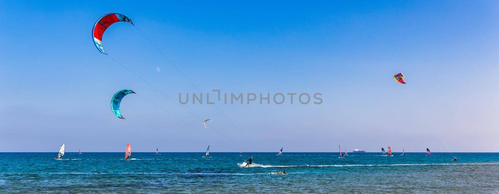 Surfers in Prasonisi Beach in Rhodes island, Greece. Kiteboarder kitesurfer athlete performing kitesurfing kiteboarding tricks. Prasonisi Beach is popular location for surfing. Greece
