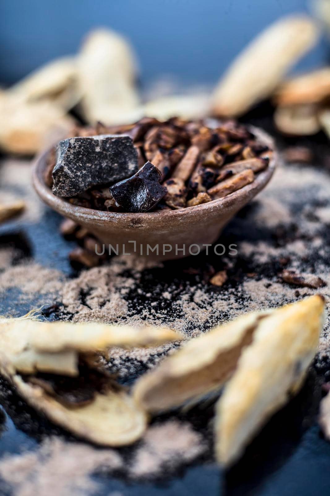 Popular Indian and Asian mukhwas or mouth freshener i.e. Aam Ki Ghuthli Ka Mukhwas consisting of ghee and hard-boiled mango seeds in a bowl on a wooden surface.Along with some raw dried mango seeds.