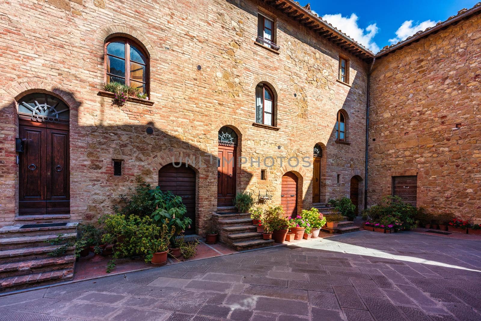 Cozy street decorated with colorful flowers, Pienza, Tuscany, Italy, Europe. Narrow street in the charming town of Pienza in Tuscany. Beautiful streets of the small and historic village Pienza, Italy