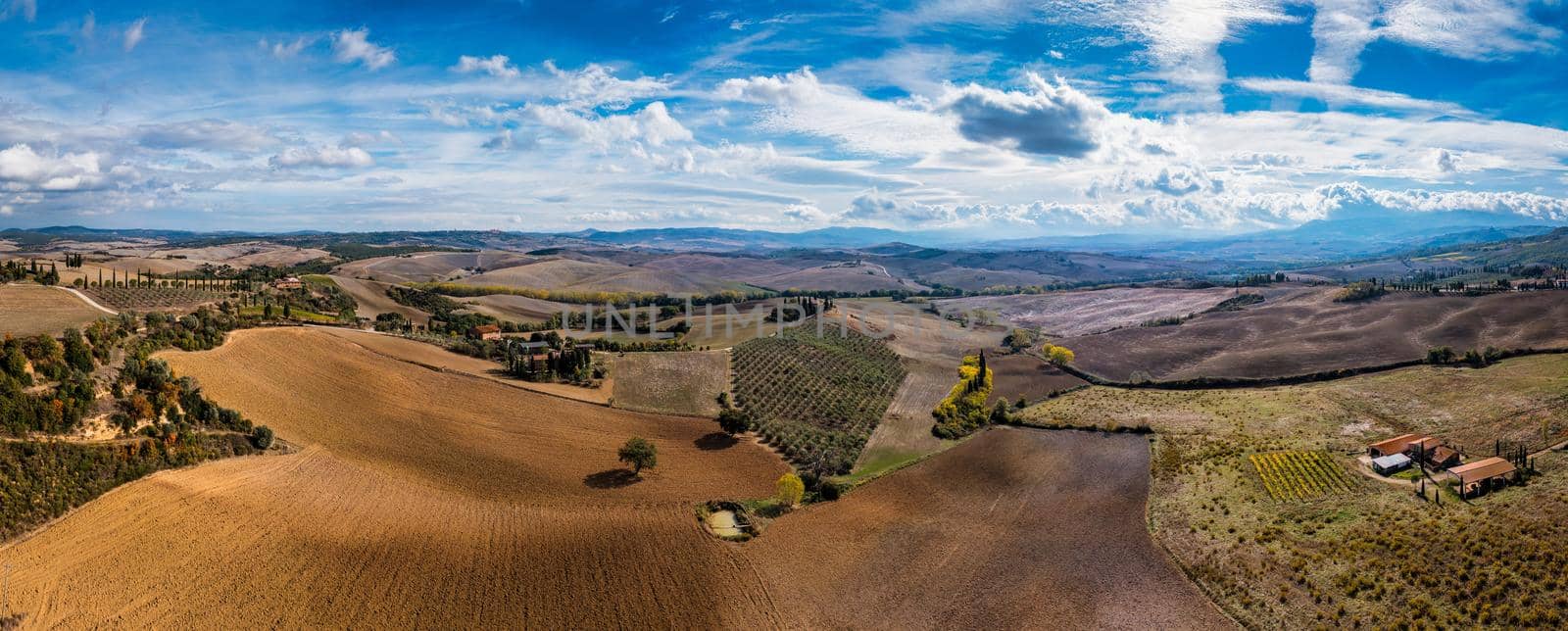 Well known Tuscany landscape with grain fields, cypress trees and houses on the hills at sunset. Summer rural landscape with curved road in Tuscany, Italy, Europe