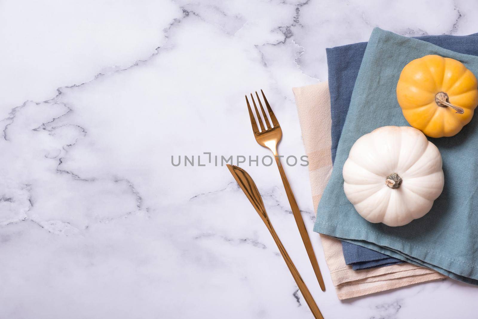 Autumn flat lay with napkins and cutlery and decorative pumpkins on marble background top view. High quality photo