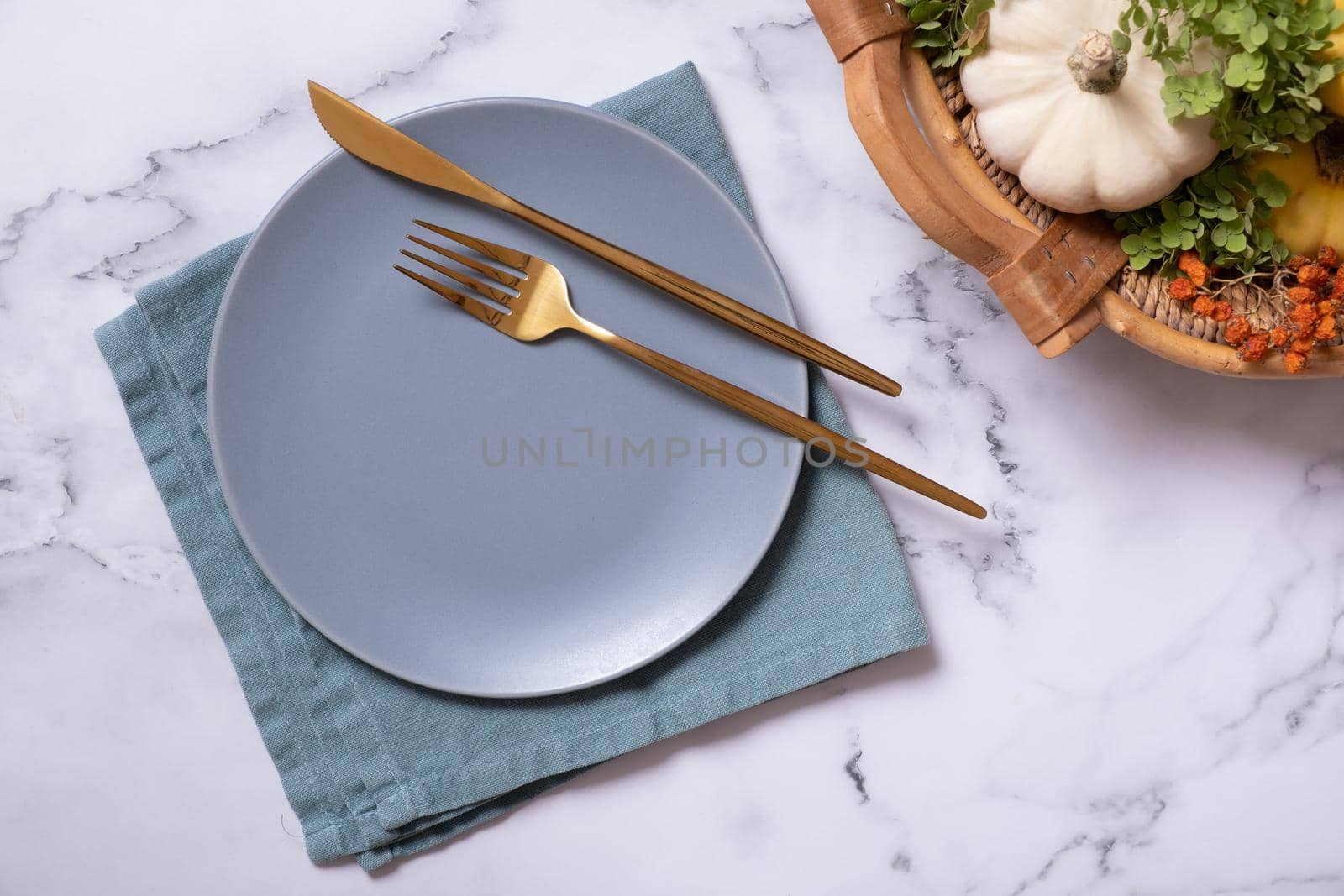 Autumn flat lay with plate and cutlery and decorative pumpkins on marble background top view.