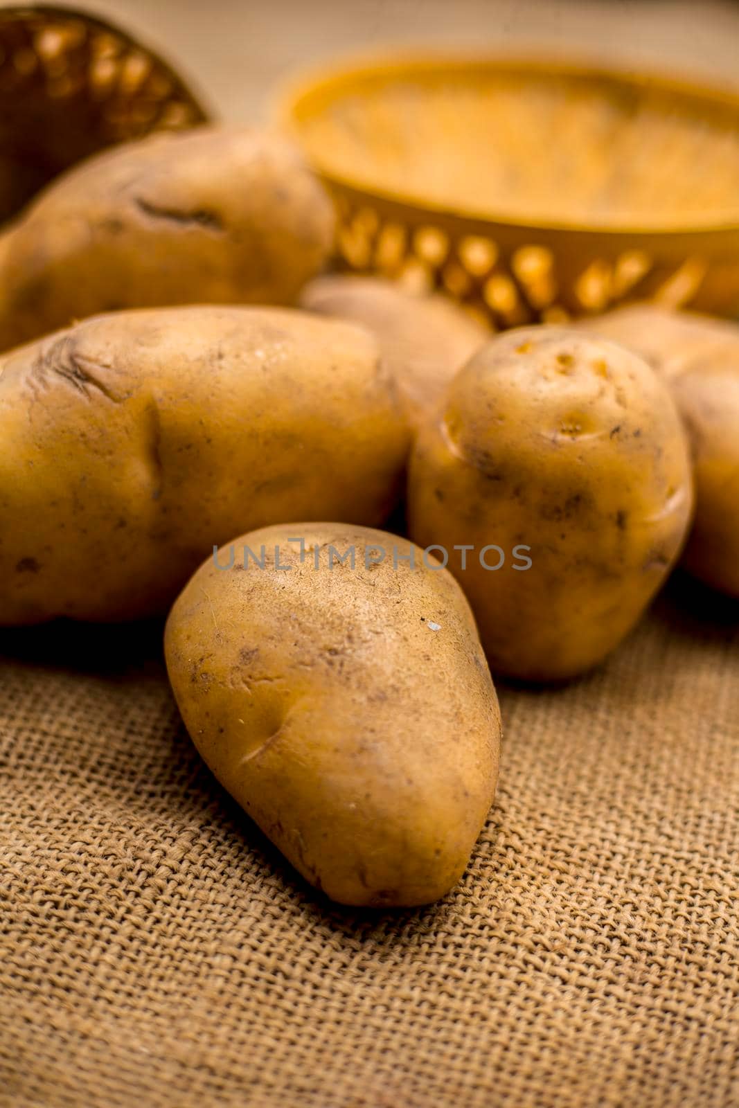 Close up shot of potato or aloo or alu on jute bag surface along with two vegetable and fruit hampers. by mirzamlk