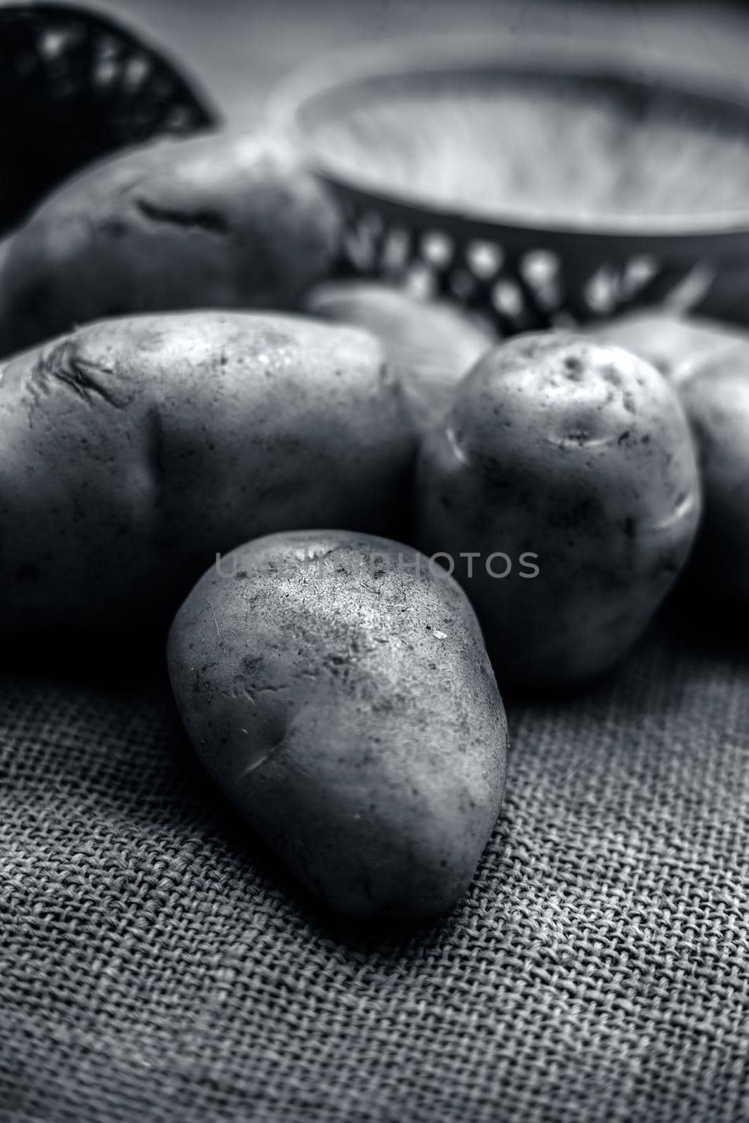 Close up shot of potato or aloo or alu on jute bag surface along with two vegetable and fruit hampers.