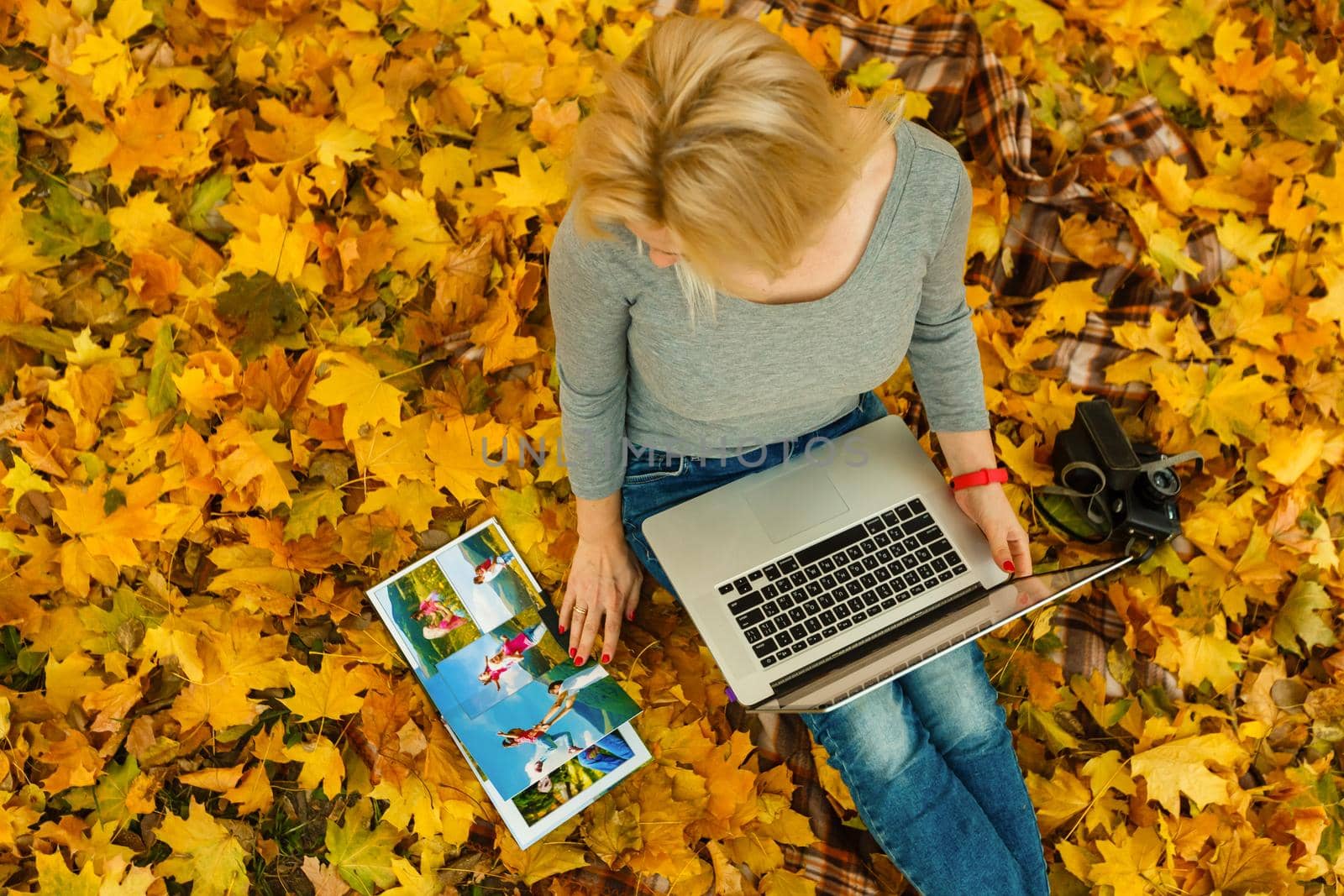 woman with laptop and photo book in autumn park by Andelov13