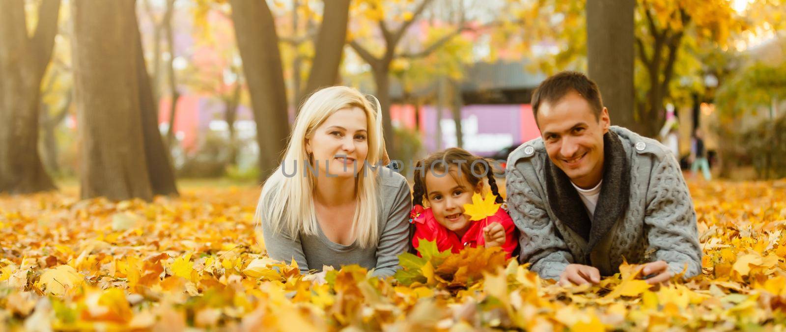 Happy family is sitting in beautiful autumn park by Andelov13