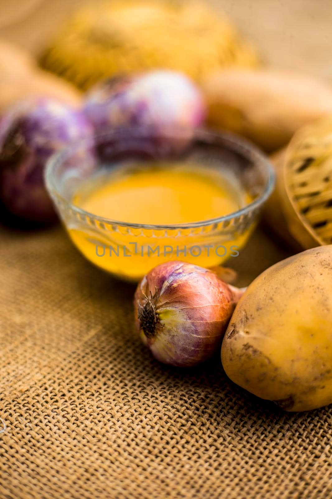 Best earth growth-boosting potion consisting of ingredients which are potato juice and onion juice in a glass bowl along with raw potato and onion on the surface.