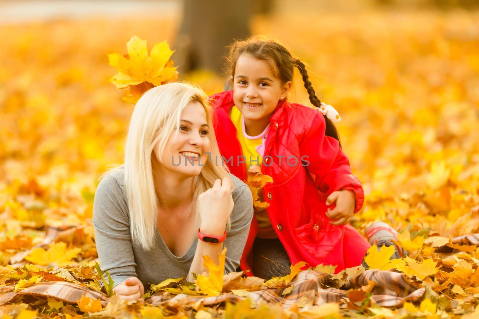 Happy parent and kid holding autumn yellow leaves outdoor. by Andelov13