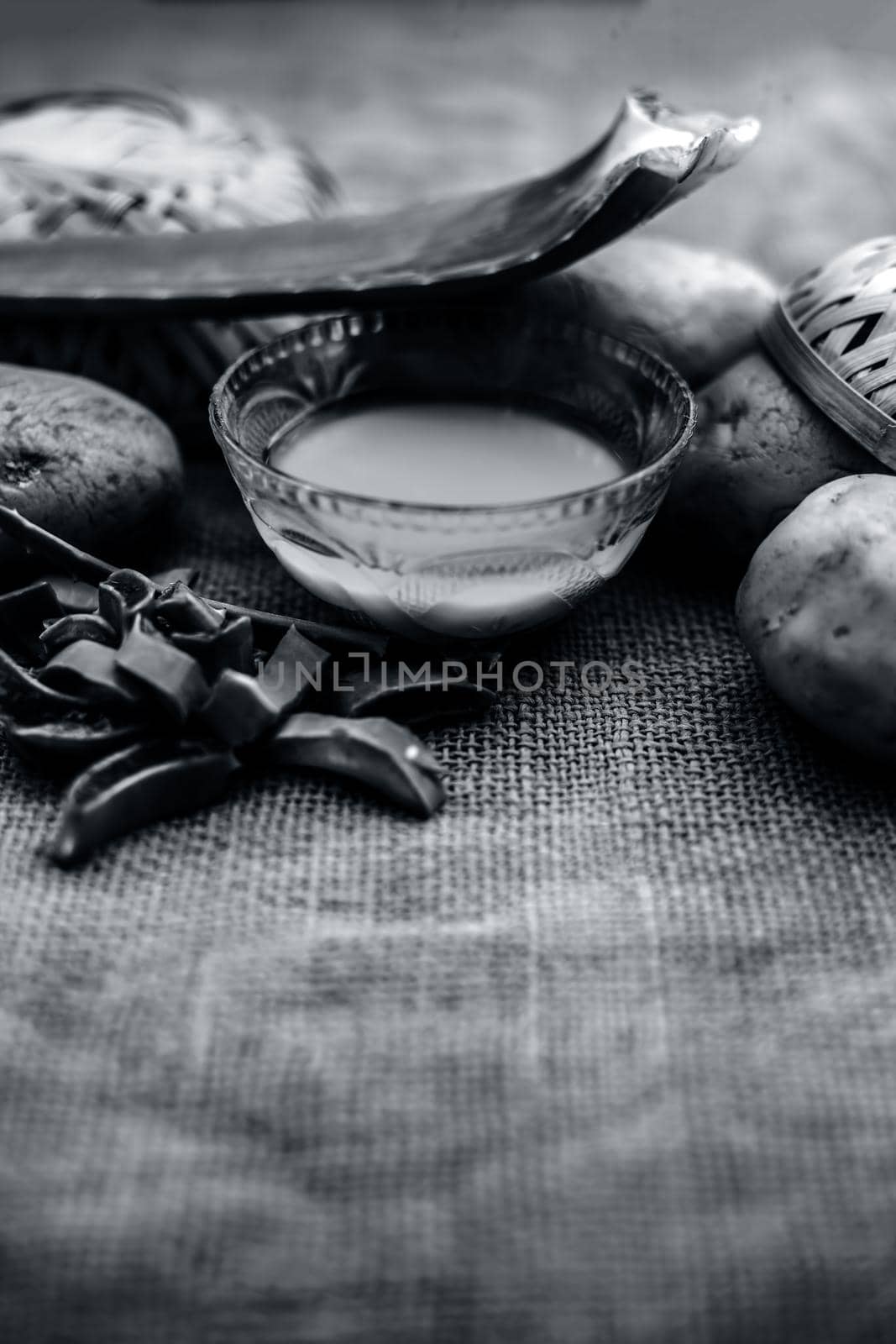 Homemade conditioner and shampoo for dandruff and scalp cleaning on jute bag's surface i.e. potato juice well mixed with aloe vera gel in a glass bowl along with raw potato and some aloe vera leaf.