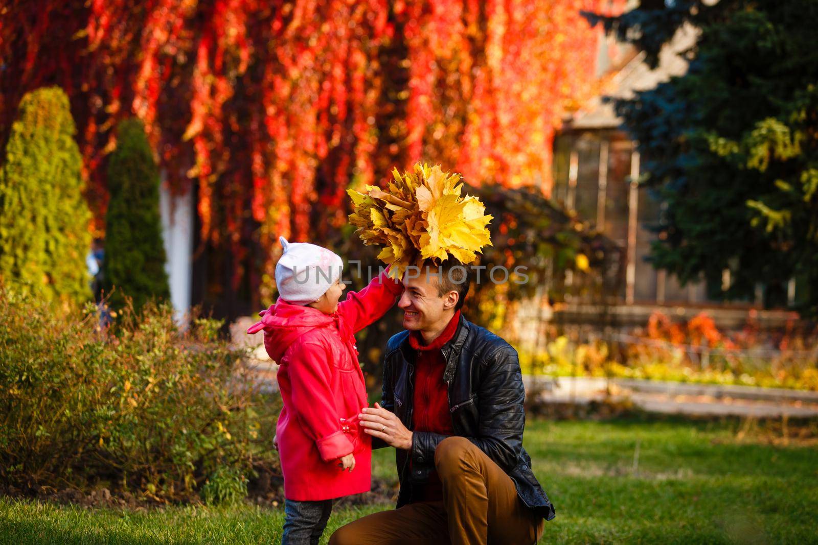 Happy family. daughter kissing and hugging her dad on a walk in the autumn leaf fall in park. by Andelov13