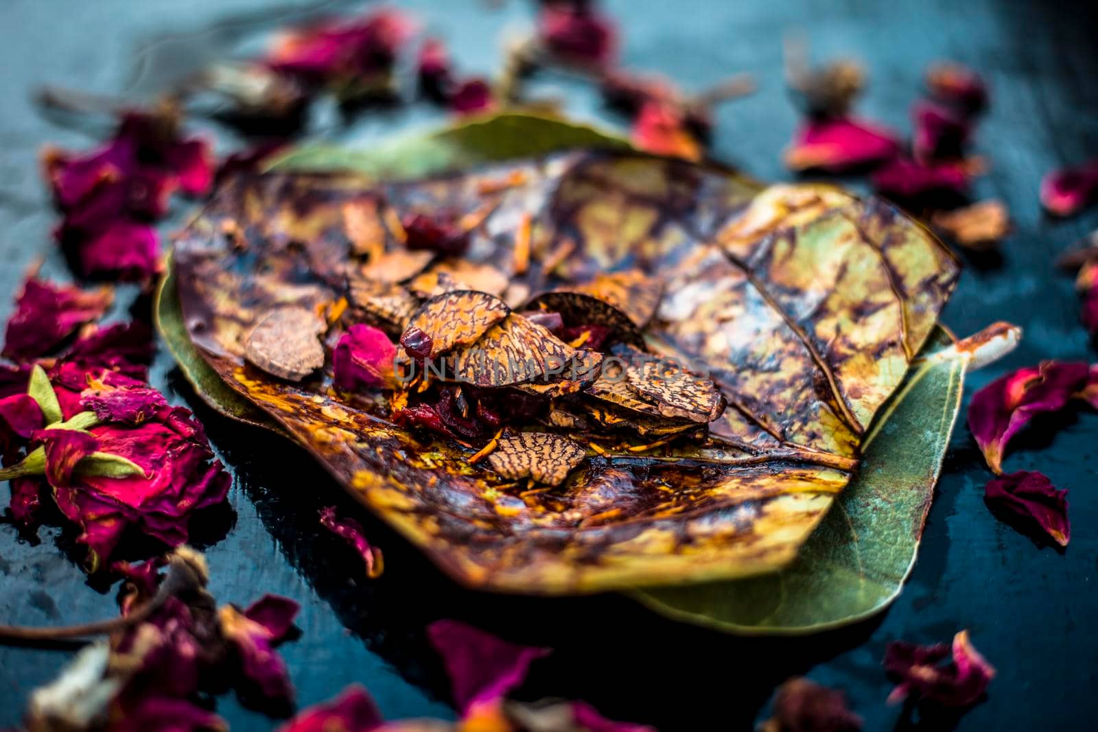 Close up of Famous Indian traditional masala pan or meetha pan on black surface with some rose water consisting of coated sauf,supari,sweeteners and some coconut powder.