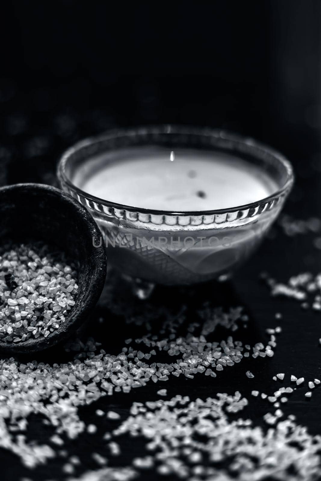 Curd or yogurt and oats face mask on the woodne surface in a glass bowl along with some raw oats in a black colored clay bowl and some spread on the surface. To Exfoliate Your Skin. by mirzamlk