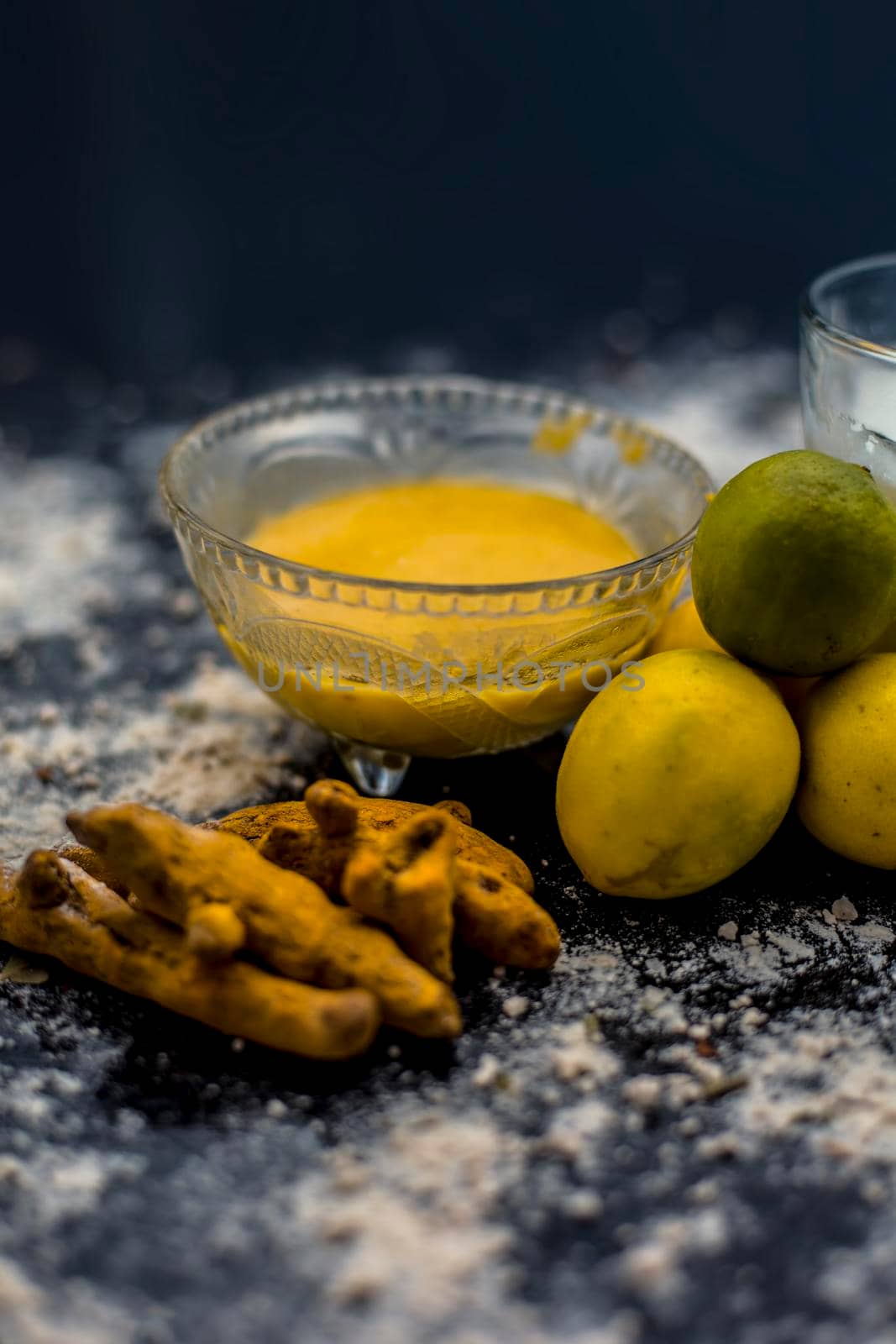 Lemon face mask on the wooden surface consisting lemon juice, gram flour or chickpea flour, turmeric or Haldi and milk in a glass bowl.For the treatment of tans. by mirzamlk