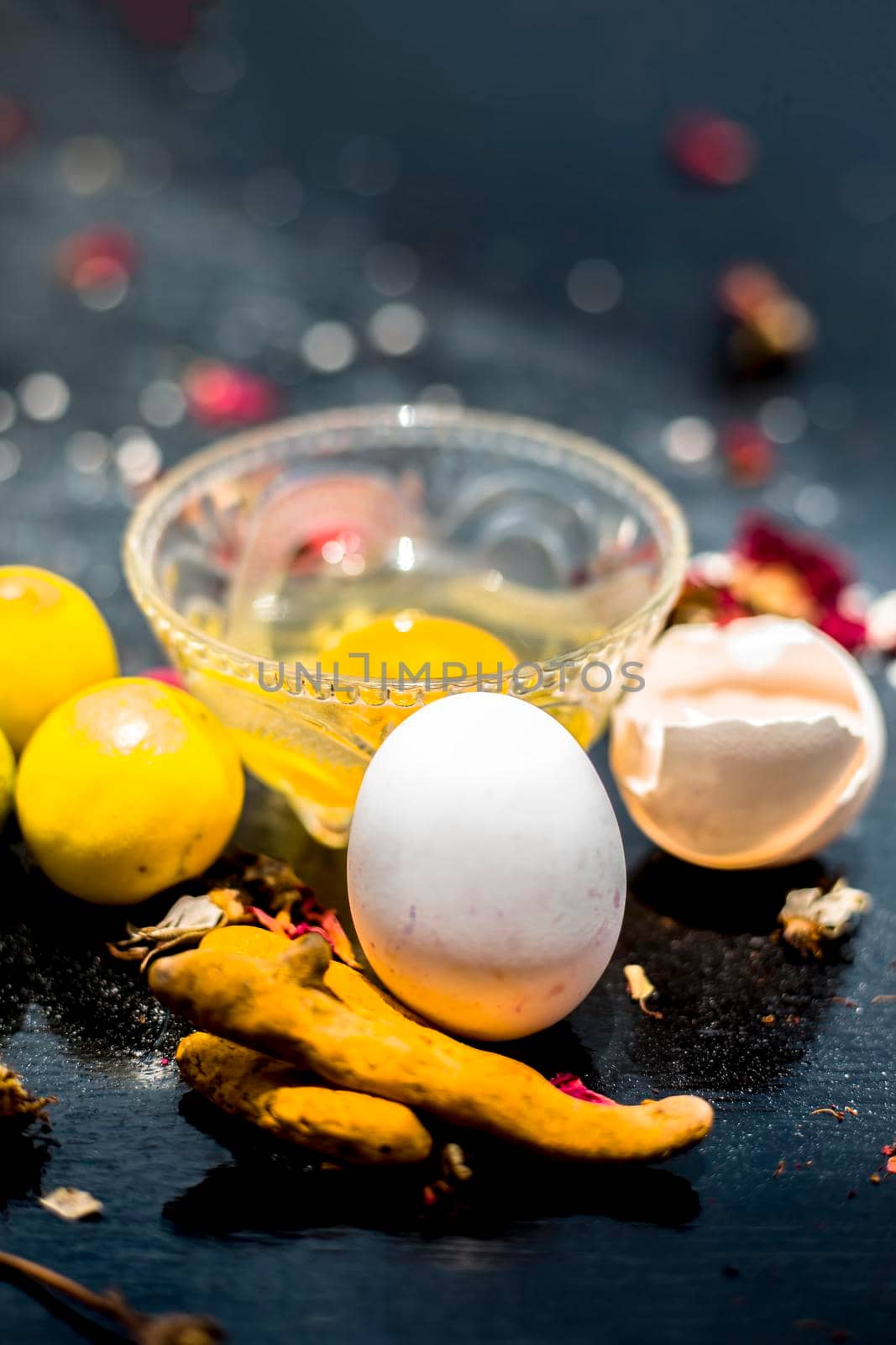 Face mask of lemon juice, honey, and curd along with some raw turmeric well mixed in a glass bowl along with entire raw ingredients on the wooden surface for acne-prone skin and blemishes. by mirzamlk