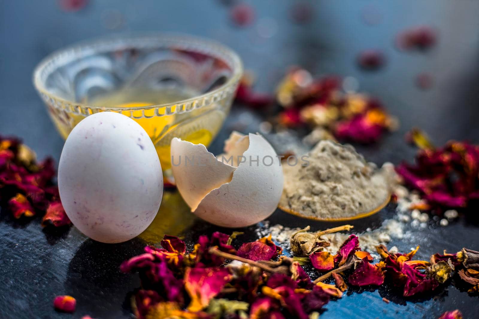 Egg and besan or chickpea flour or gram flour on wooden surface in a glass bowl along with raw egg and flour on the surface.For the treatment of lines and wrinkles.