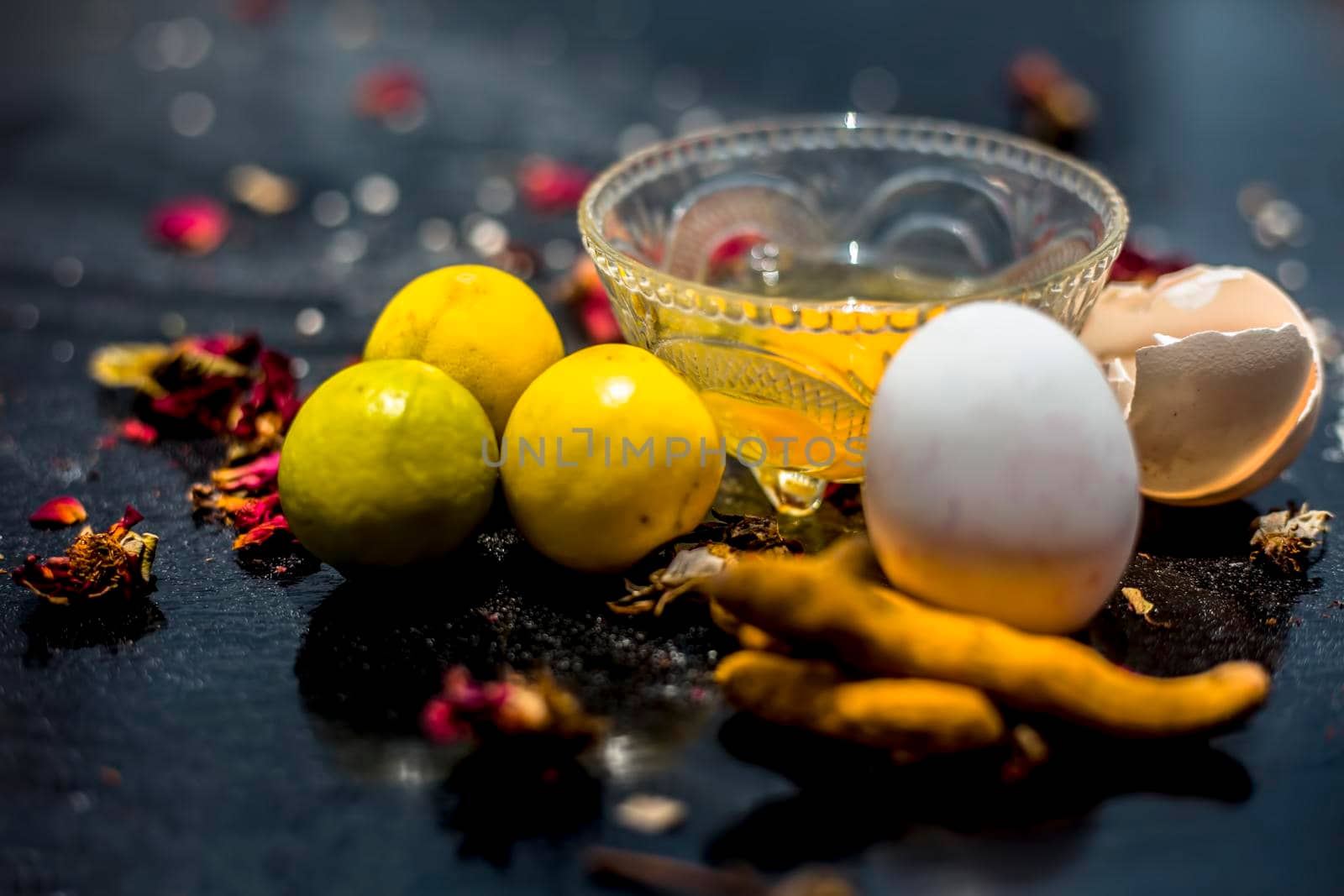 Face mask of lemon juice, honey, and curd along with some raw turmeric well mixed in a glass bowl along with entire raw ingredients on the wooden surface for acne-prone skin and blemishes. by mirzamlk