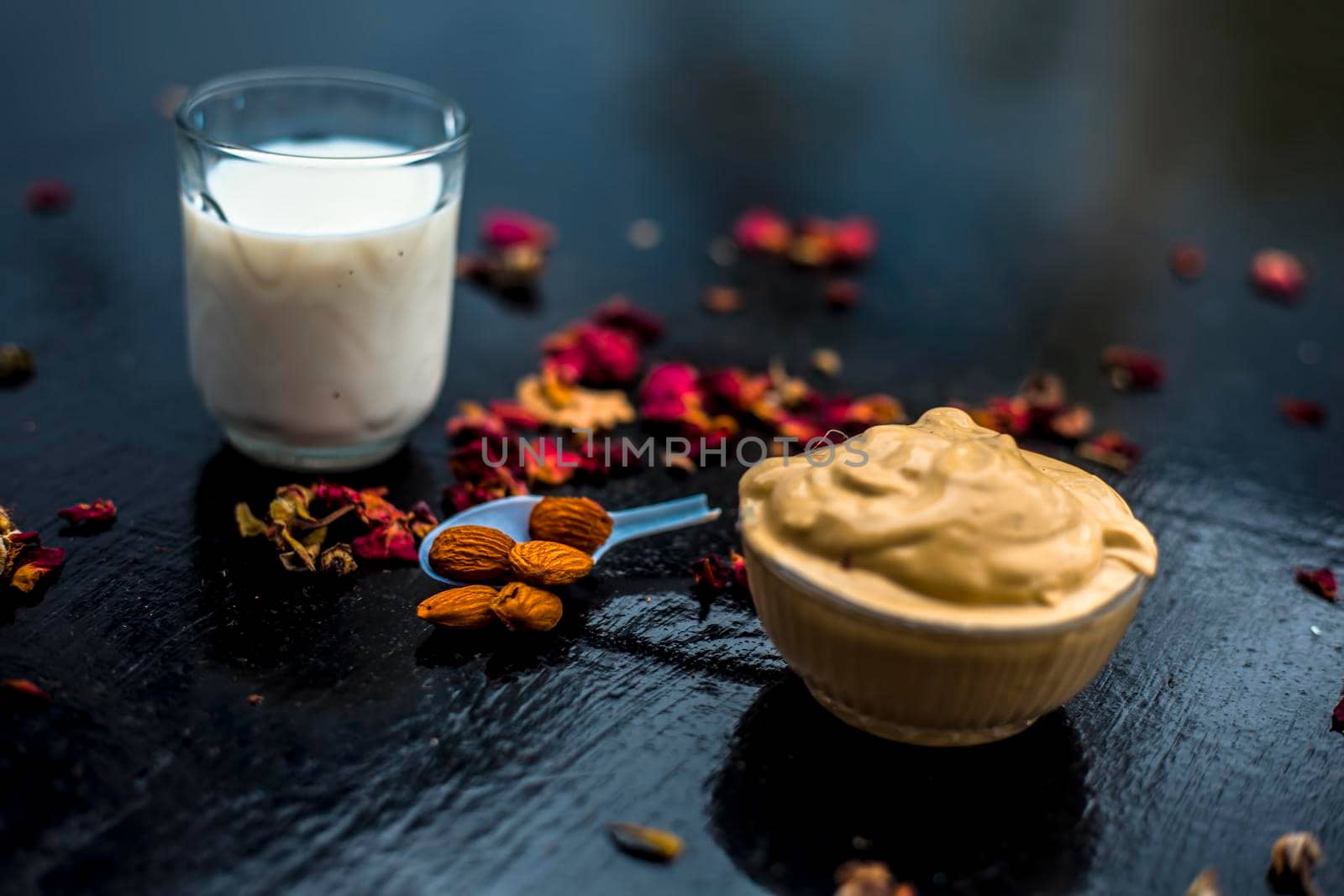 Multani mitti or fuller's earth or mulpani mitti face mask on wooden surface in glass bowl consisting of milk, almonds, and bentonite clay.For the treatment of softer skin. by mirzamlk