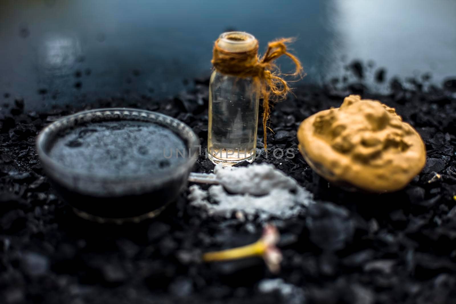 Activated charcoal face mask consisting of bentonite clay or fuller's earth or multani mitti or mulpani mitti well mixed with baking soda and coconut oil. On a wooden surface with entire constituents.