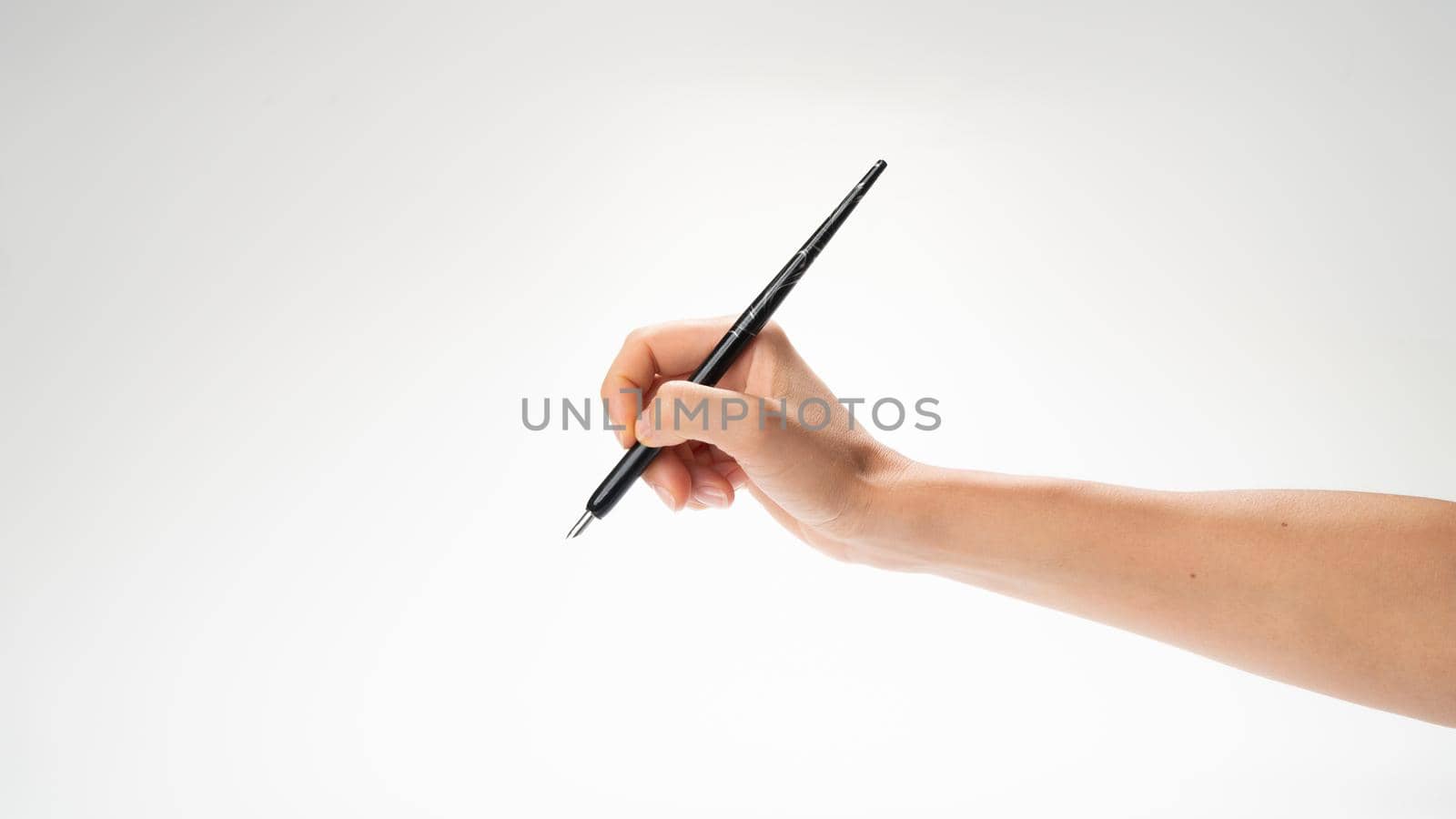 A woman's right hand holds a pen for calligraphy and writing gesture to write by voktybre