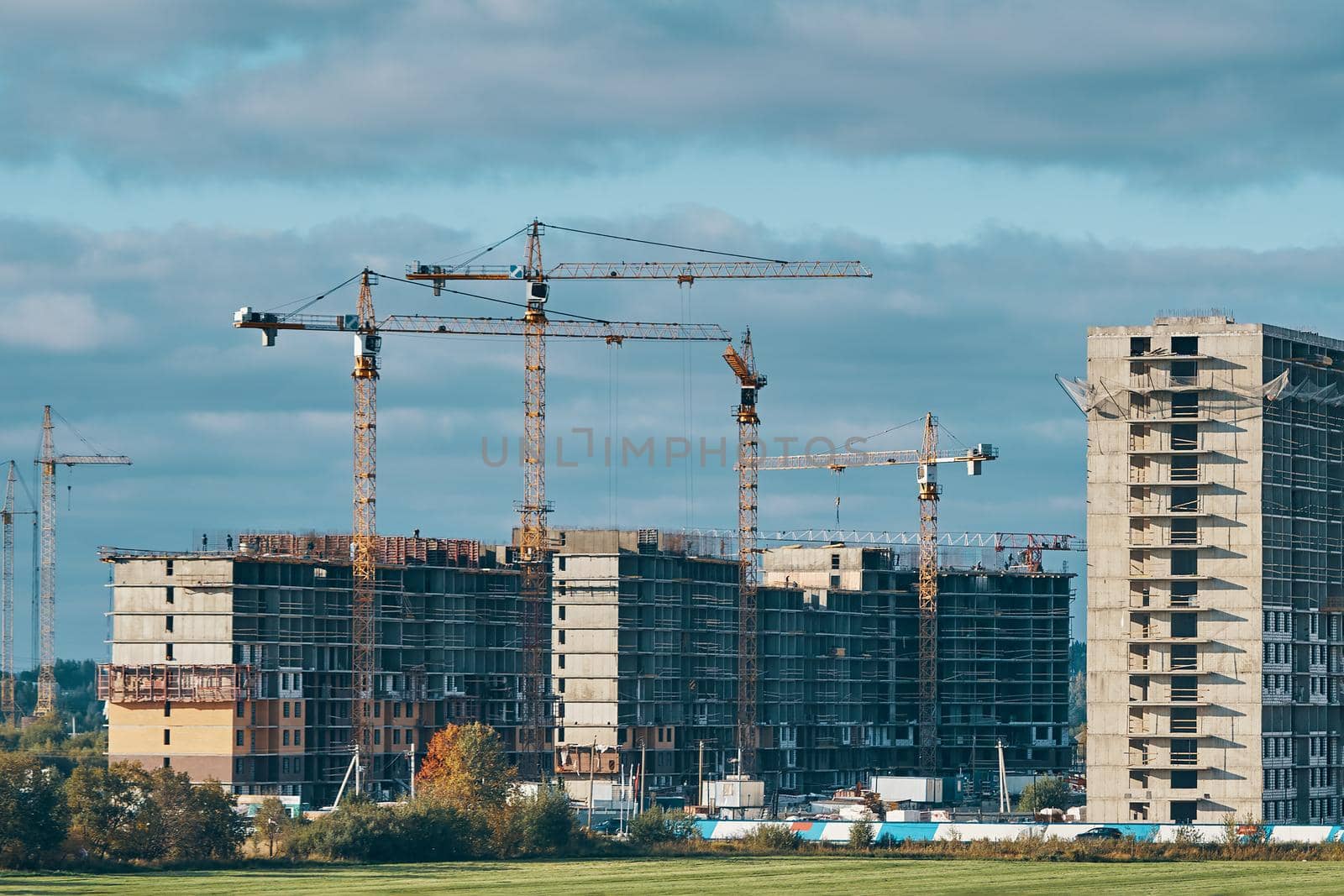 Construction site background. Industrial building cranes, multi-storey buildings of new city districts and large green field. Project of urban area.