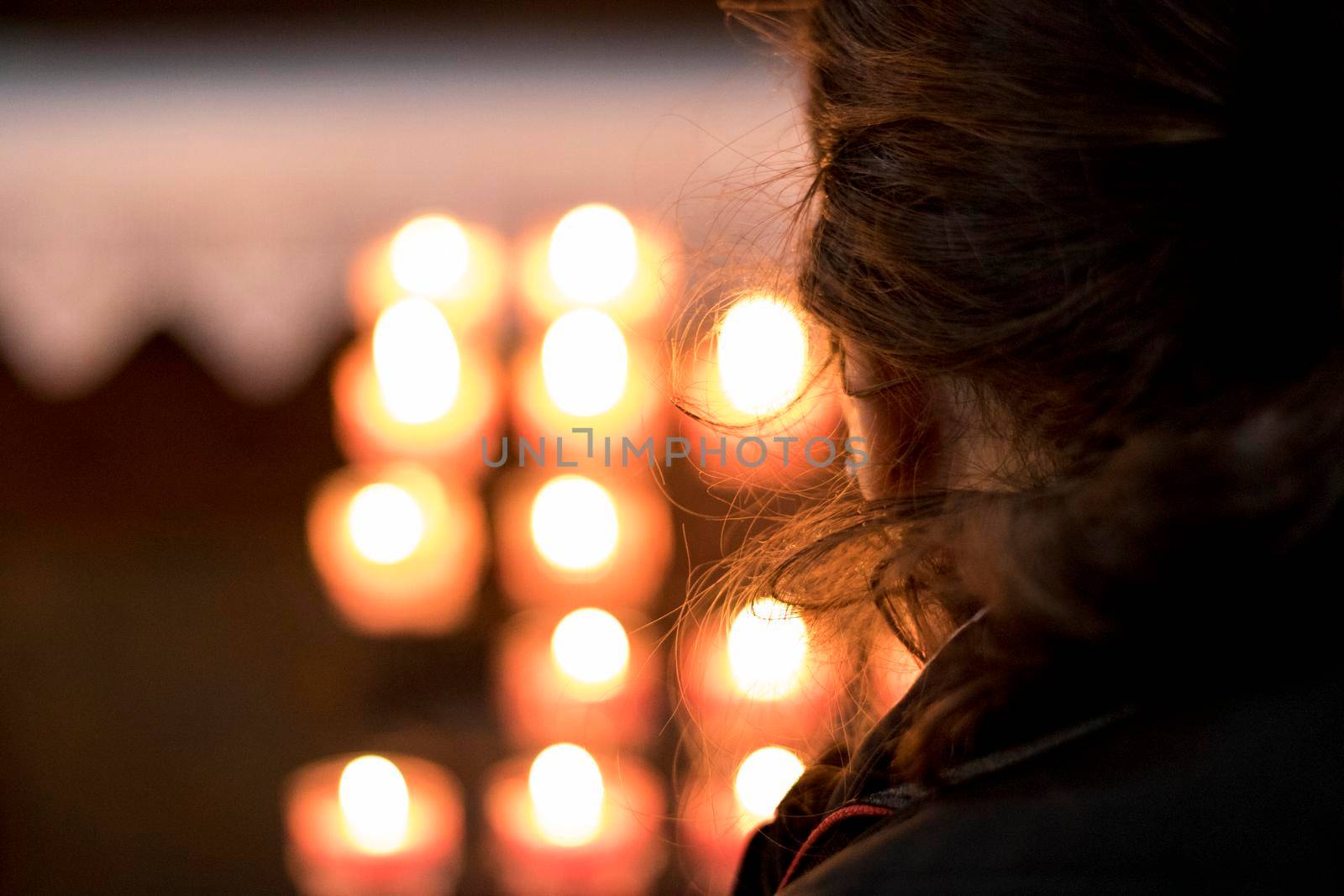 Girl looking at candles with bokeh effect in a church