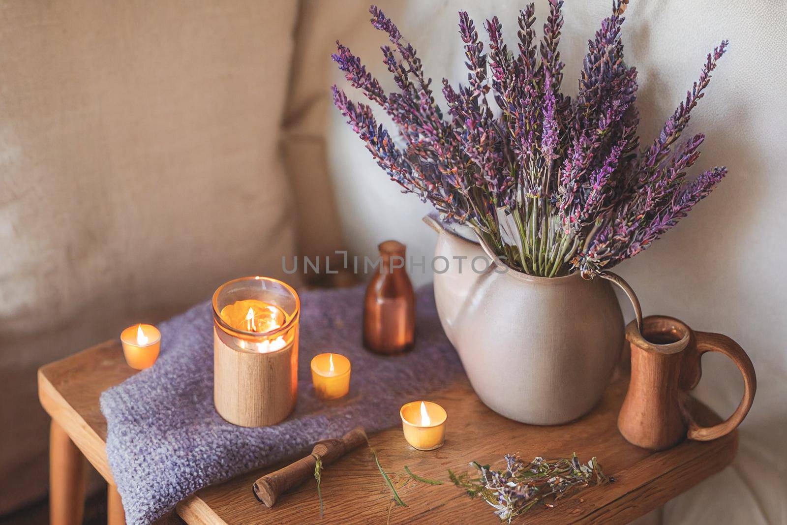 3D render of Autumn hygge home decor arrangement, concept of hygge and coziness, burning white fragrance candle on tray and lavender branches in a bottle vase on table at cozy home