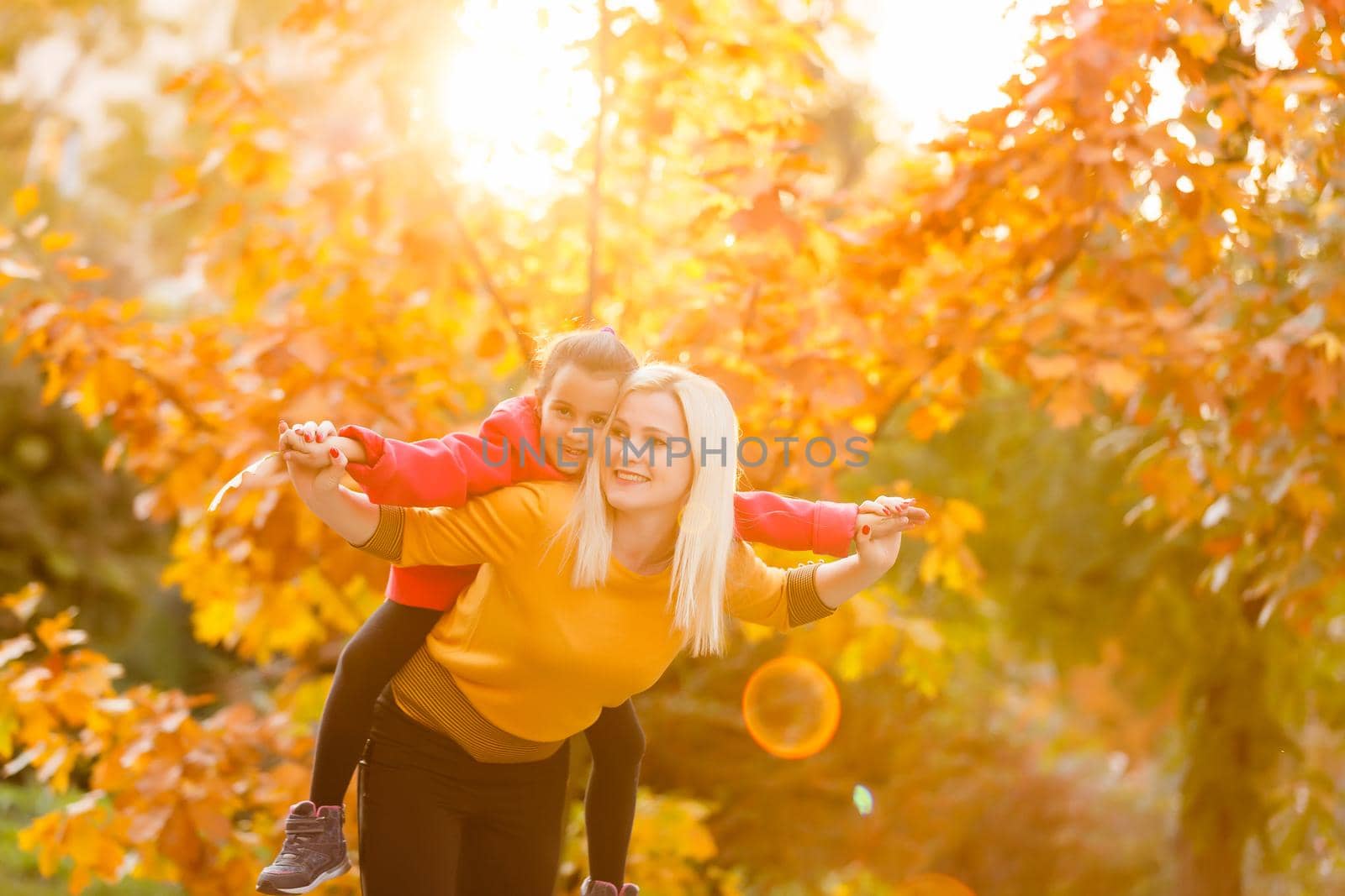 portrait of a young woman and her daughter in the autumn park