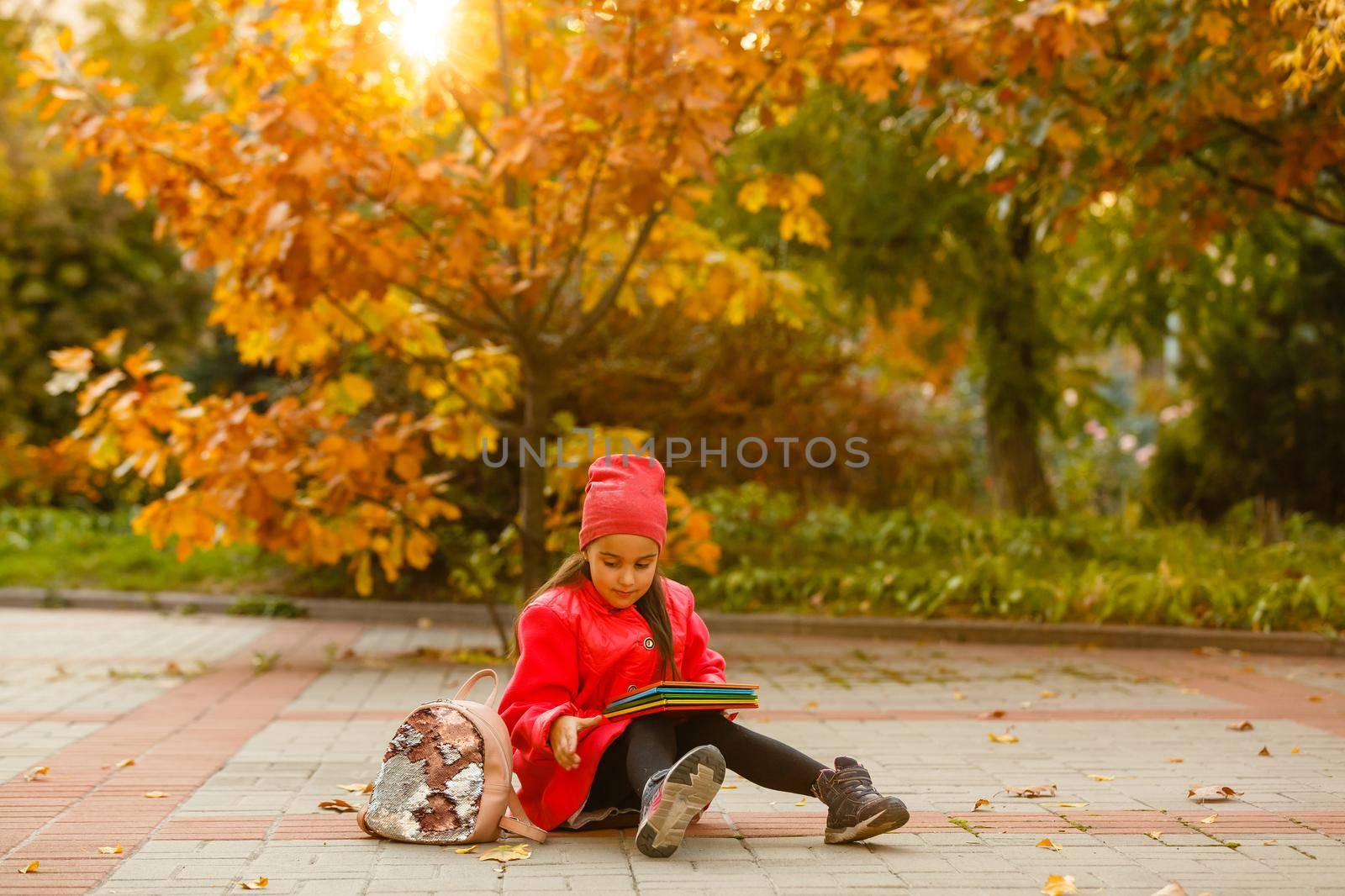 Little cute girl in autumn park. Schoolgirl with a backpack.The concept of autumn, school, study, education, childhood, back to school. by Andelov13