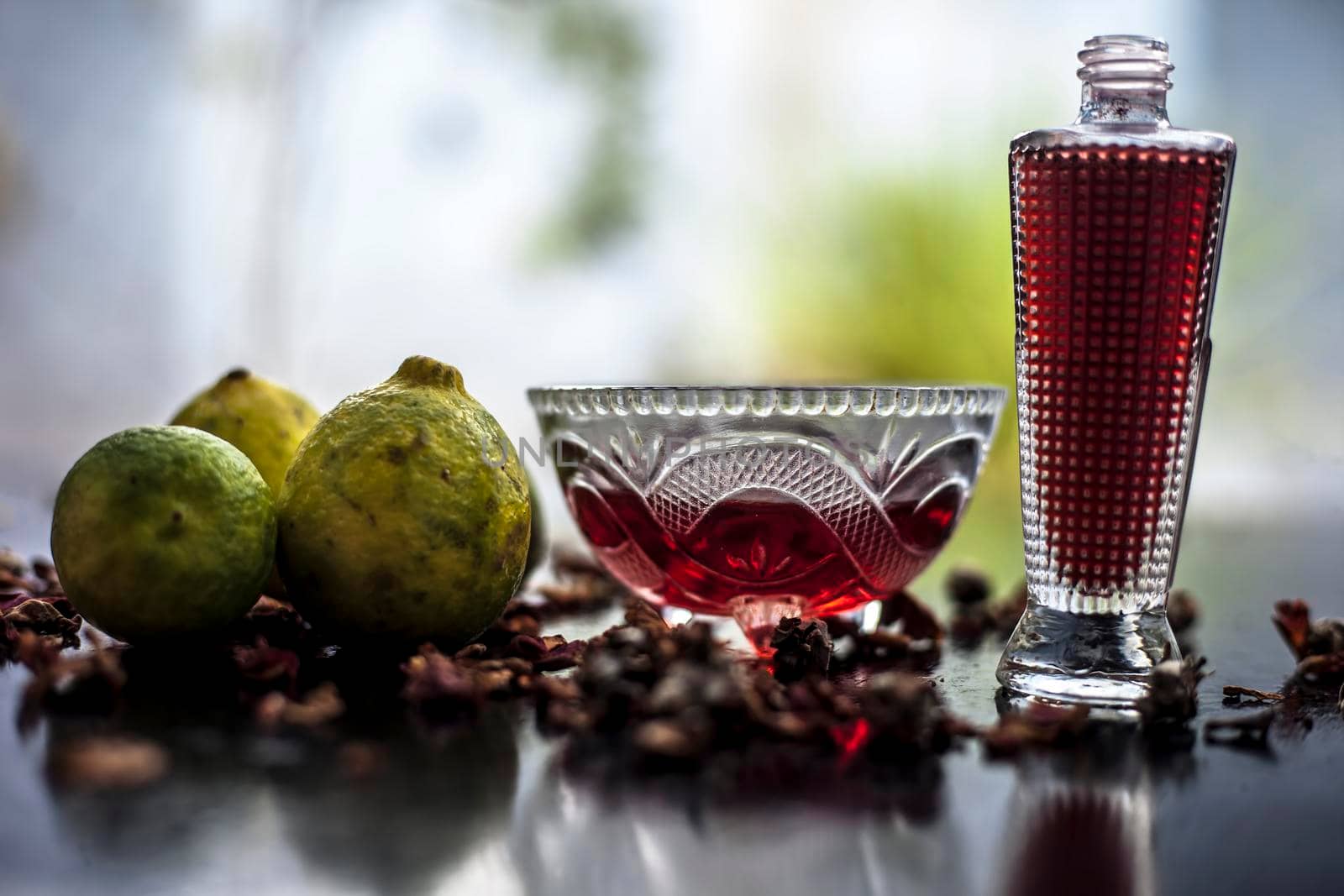 Face mask of rose water & lemon juice in a glass bowl on wooden surface along with some fresh lemons and a bottle of rose water along with,For the treatment of acne and pimple.