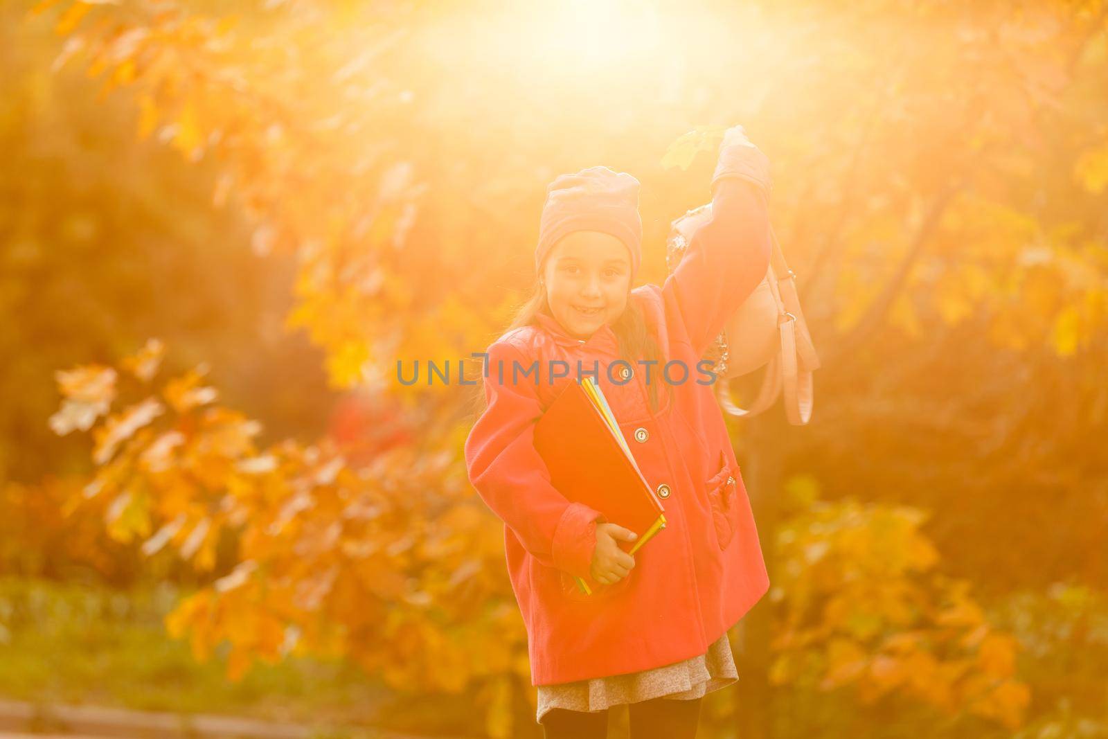 Adorable little schoolgirl studying outdoors on bright autumn day. Young student doing her homework. Education for small kids. Back to school concept.