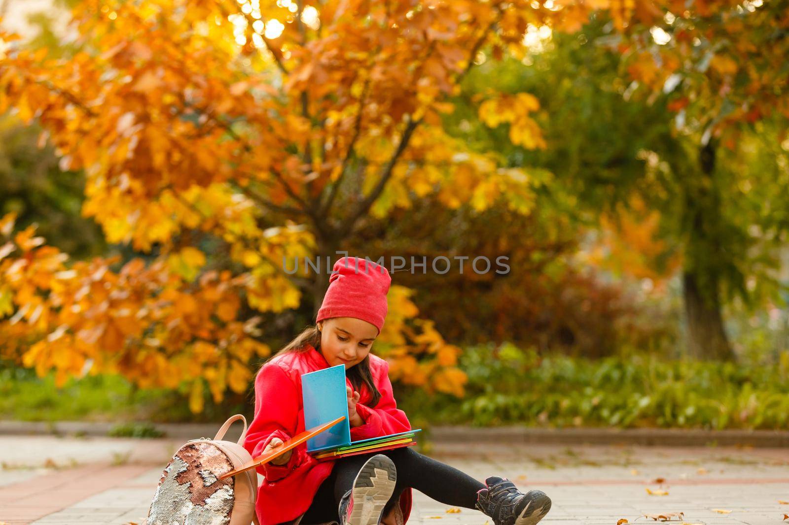 Little cute girl in autumn park. Schoolgirl with a backpack.The concept of autumn, school, study, education, childhood, back to school. by Andelov13