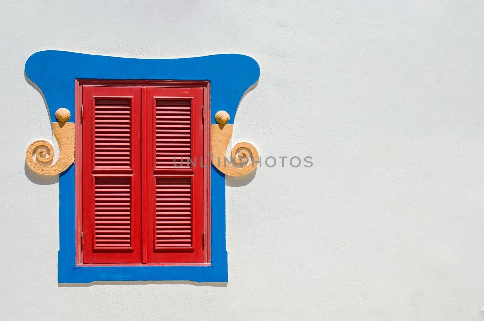 A carved wooden window with shutters closed on a white wall