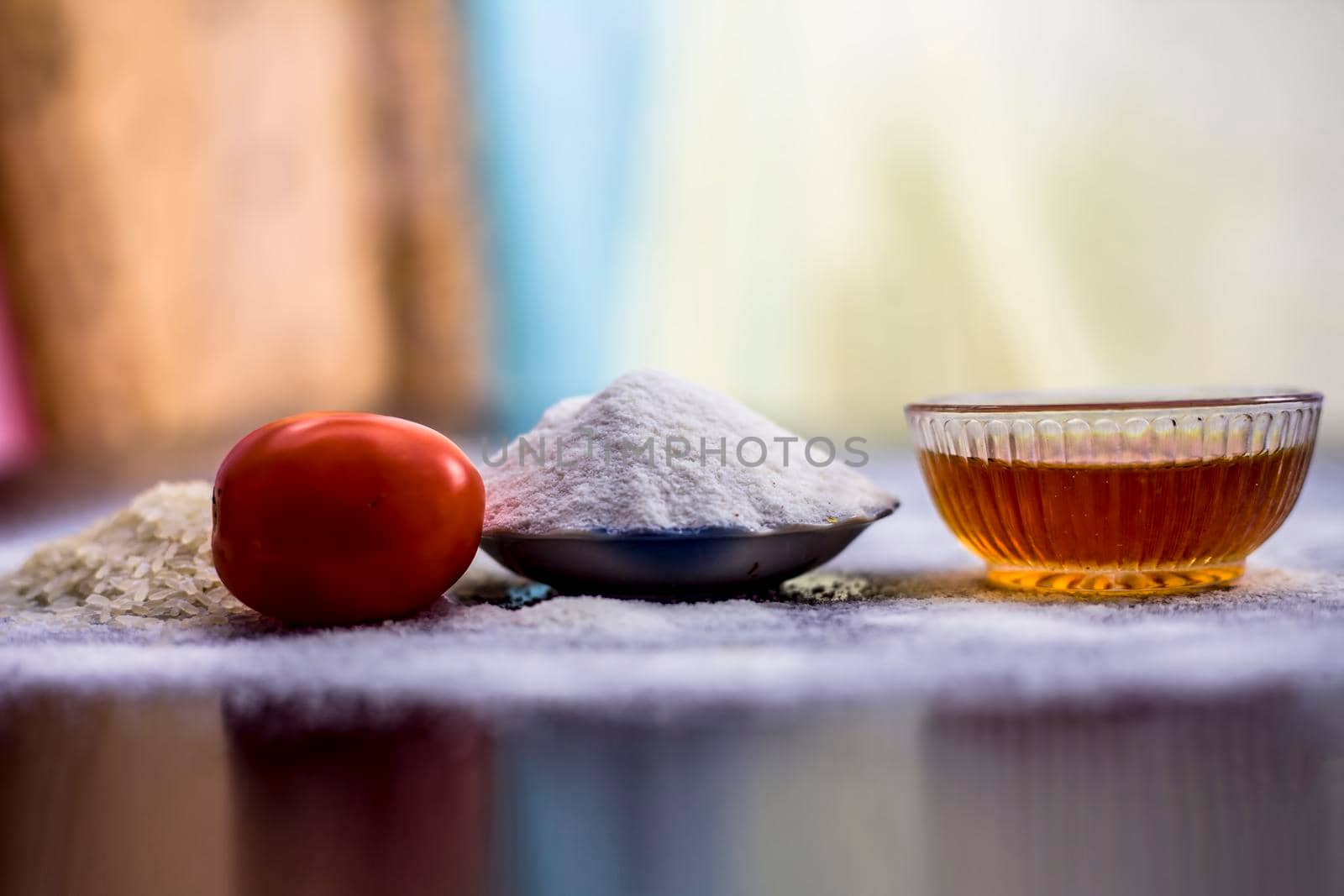 Face pack of rice flour and tomato in a glass bowl on wooden surface along with raw rice,tomato and rice flour.Used for the treatment of oily skin. by mirzamlk