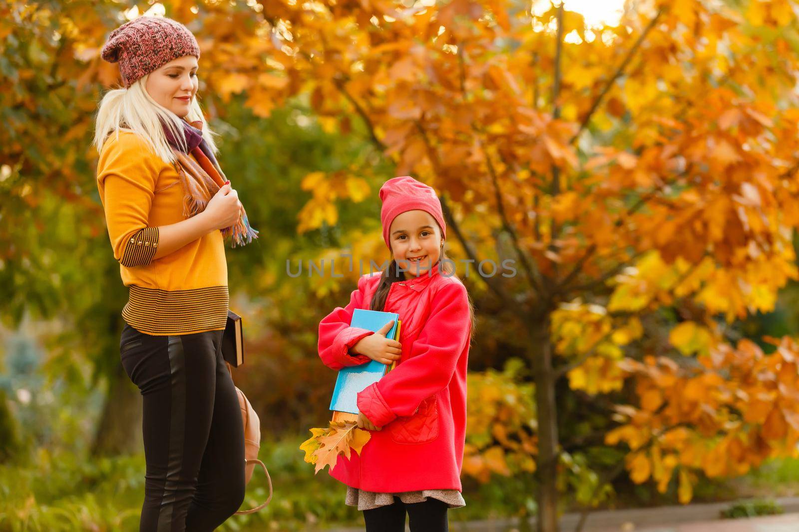 Parent take child to school. Pupil of primary school with backpack outdoors. Mother and daughter go hand in hand. Back to school. First day of fall. Elementary student. Kindergarten, preschool.