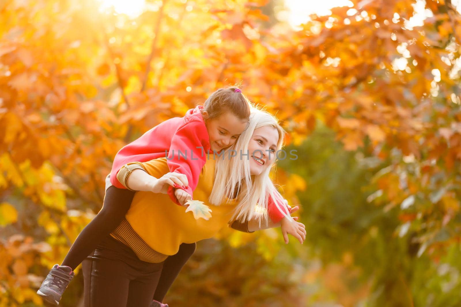 portrait of a young woman and her daughter in the autumn park