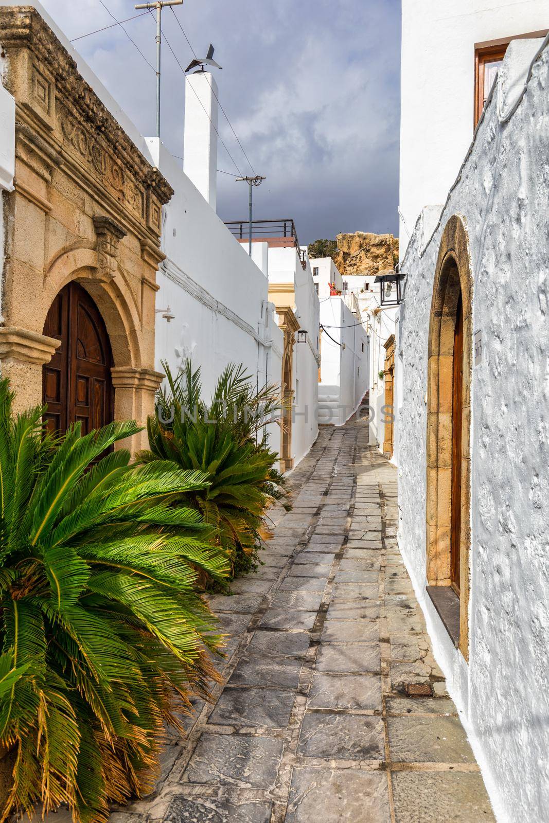 Narrow street in Lindos town on Rhodes island, Dodecanese, Greece. Beautiful scenic Lindos old ancient white houses with flowers. Famous tourist destination in South Europe. Lindos, Rhodes, Greece.