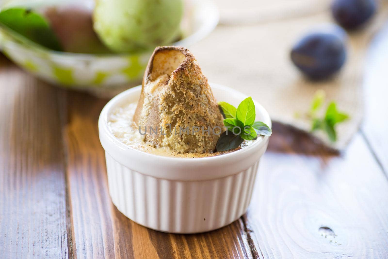 pear baked in curd dough in a small ceramic form, on a wooden table.