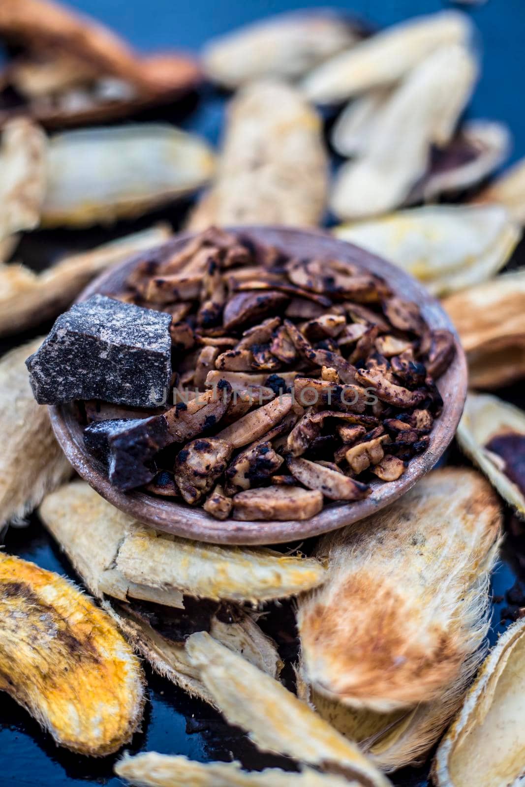 Popular Indian and Asian mukhwas or mouth freshener i.e. Aam Ki Ghuthli Ka Mukhwas consisting of ghee and hard-boiled mango seeds in a bowl on a wooden surface.Along with some raw dried mango seeds.