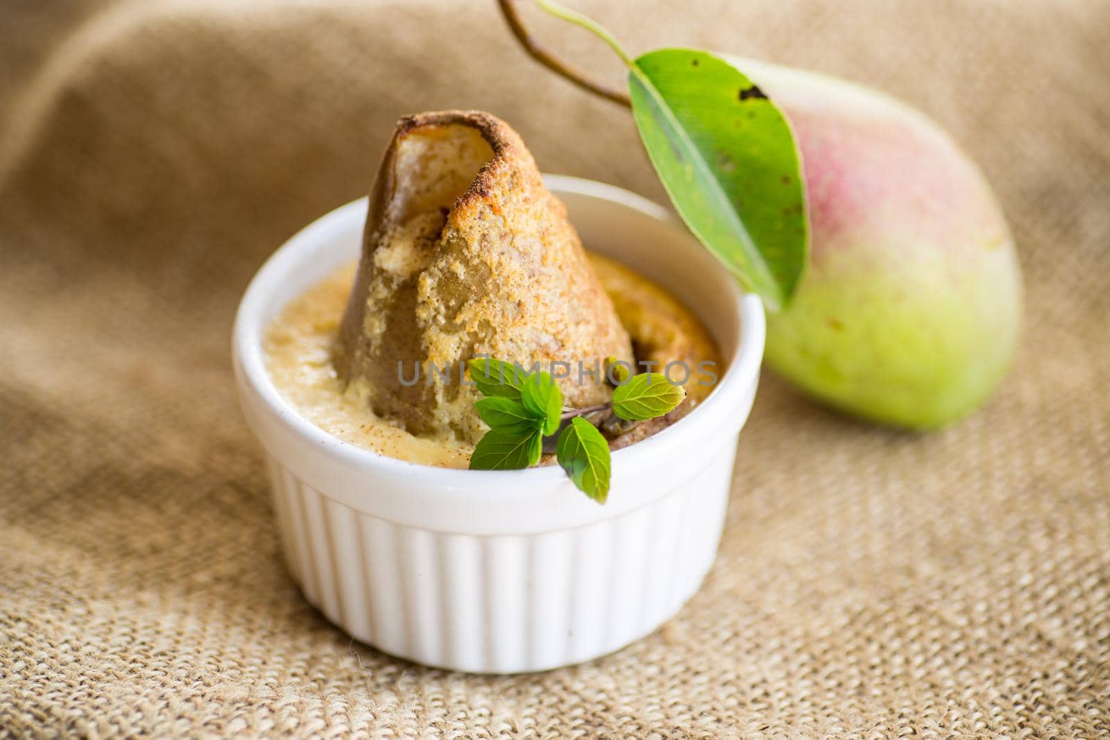 pear baked in curd dough in a small ceramic form, on burlap